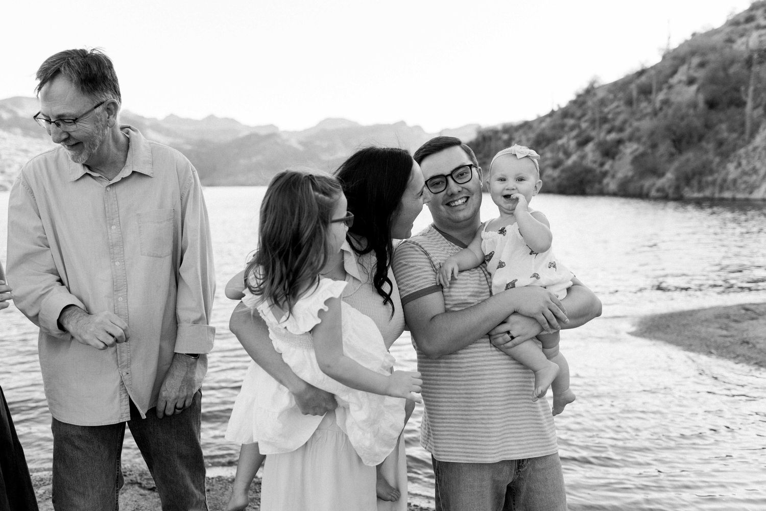 A group of people sharing joyful moments together on a beach at sunset, laughing and embracing.