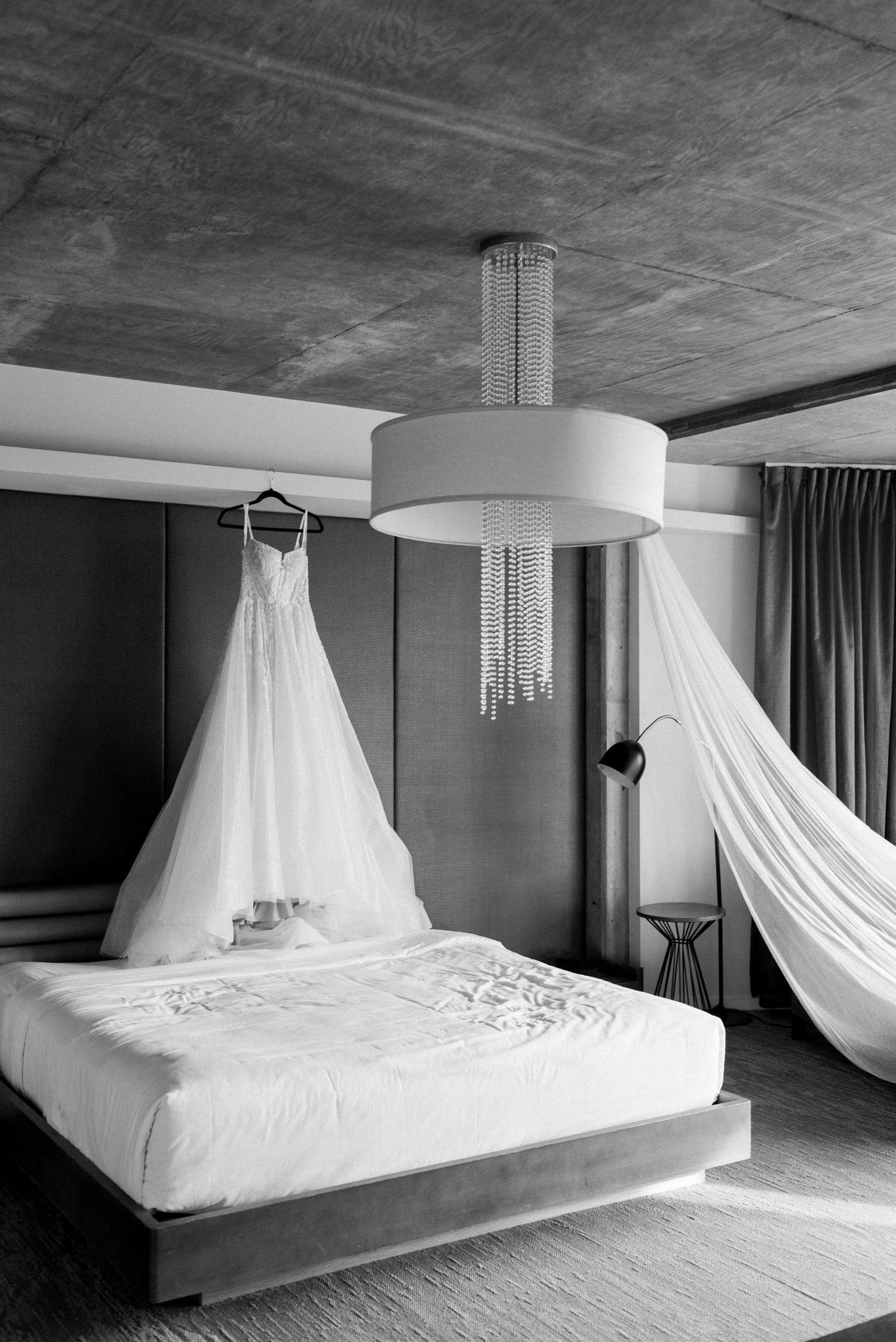 Modern minimalist bedroom with flowing white canopy drapes and contemporary lighting.