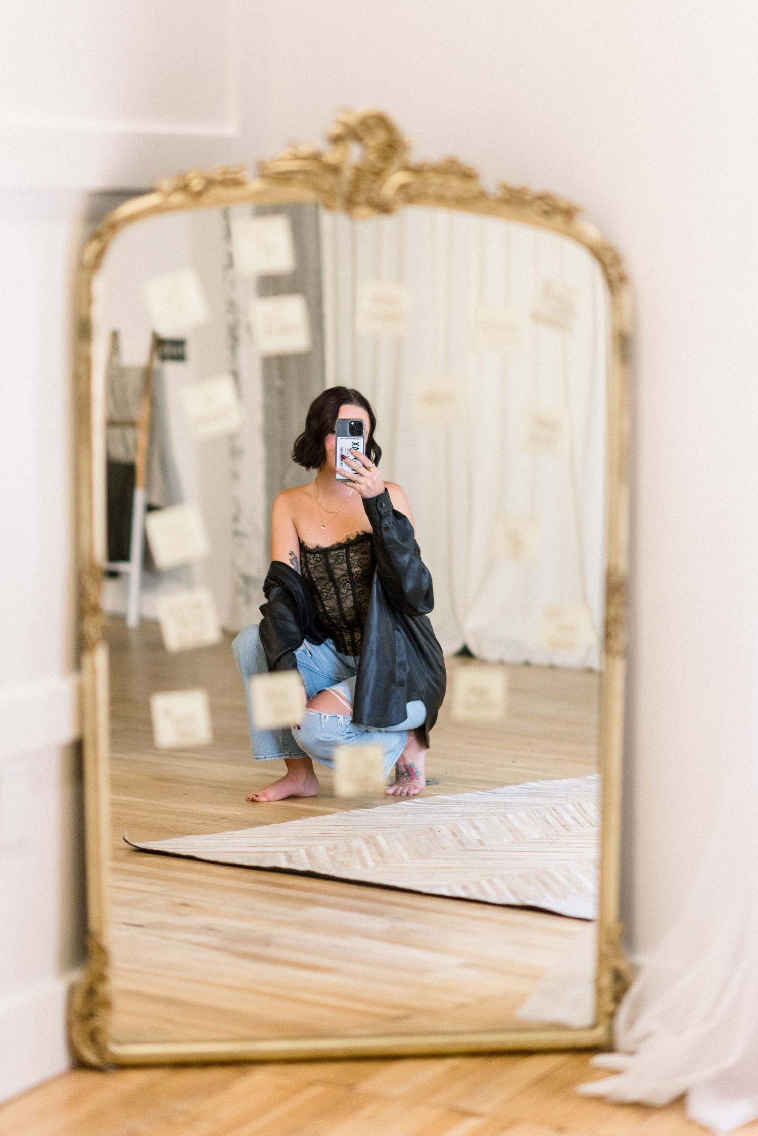 A mirror selfie showing someone wearing a black corset top and denim jacket in an ornate gold-framed mirror.