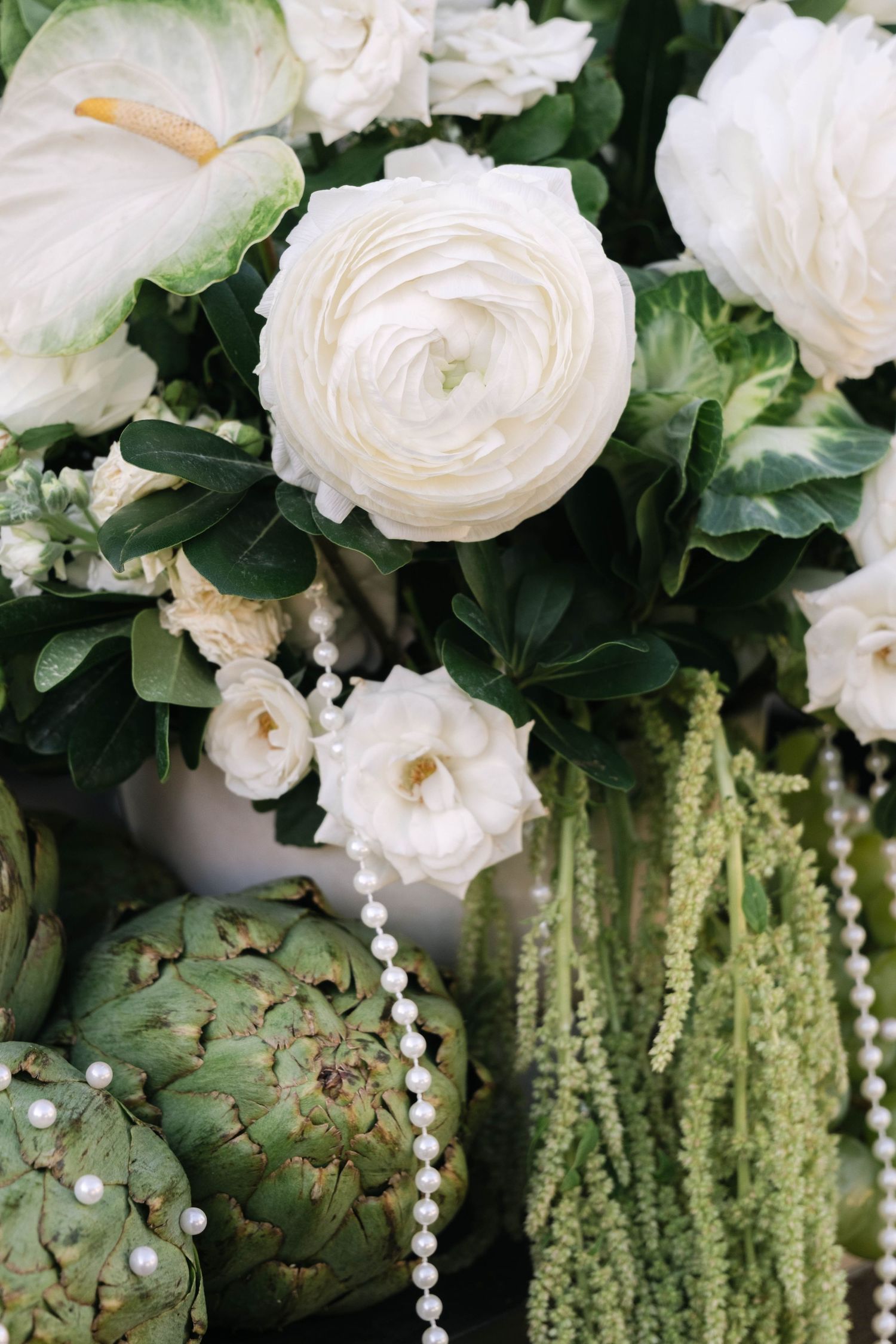 White roses and cascading greenery create an elegant floral arrangement with pearl accents.
