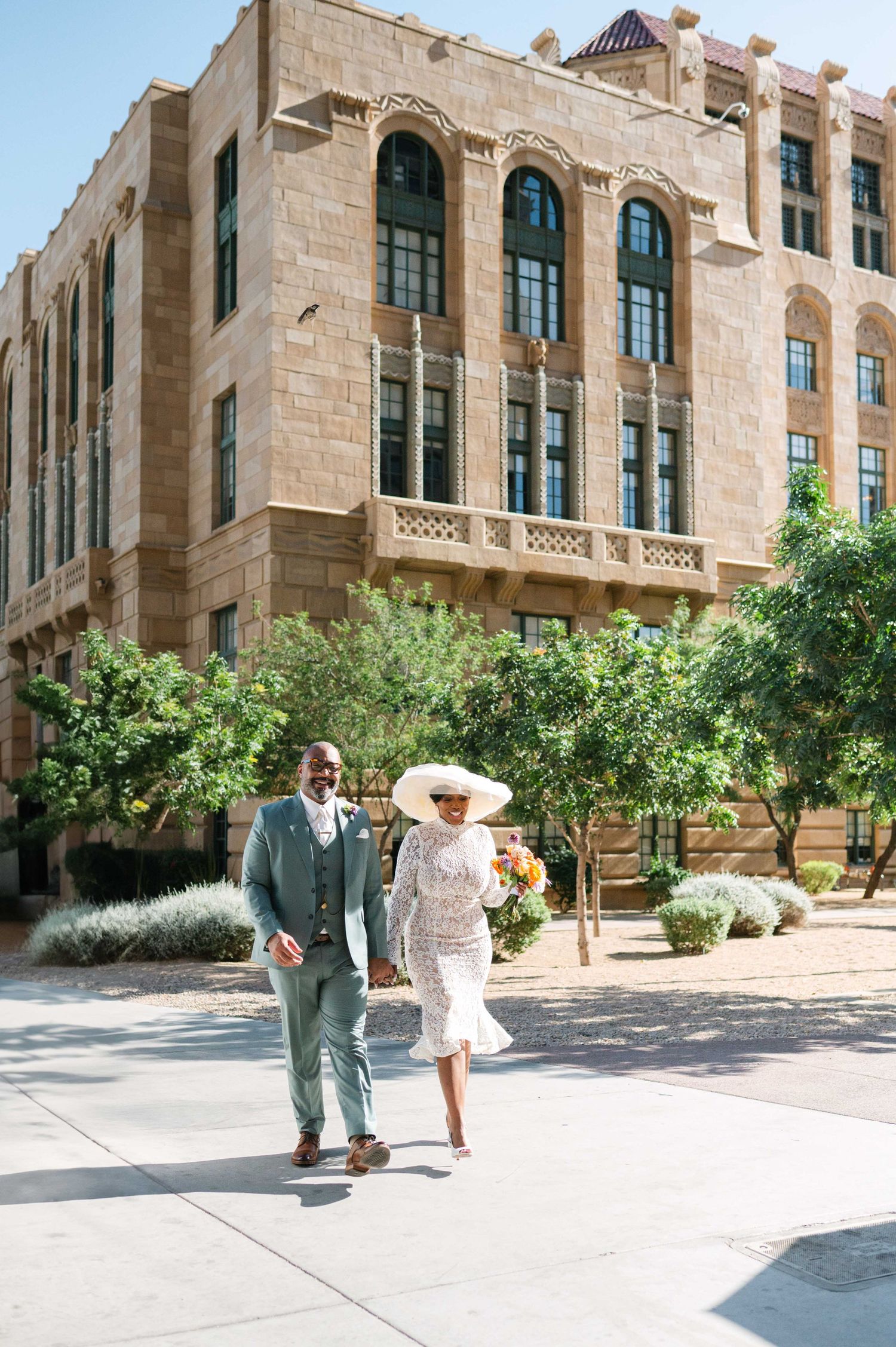A couple strolling together outside a beautiful Spanish Revival style building with ornate architecture.