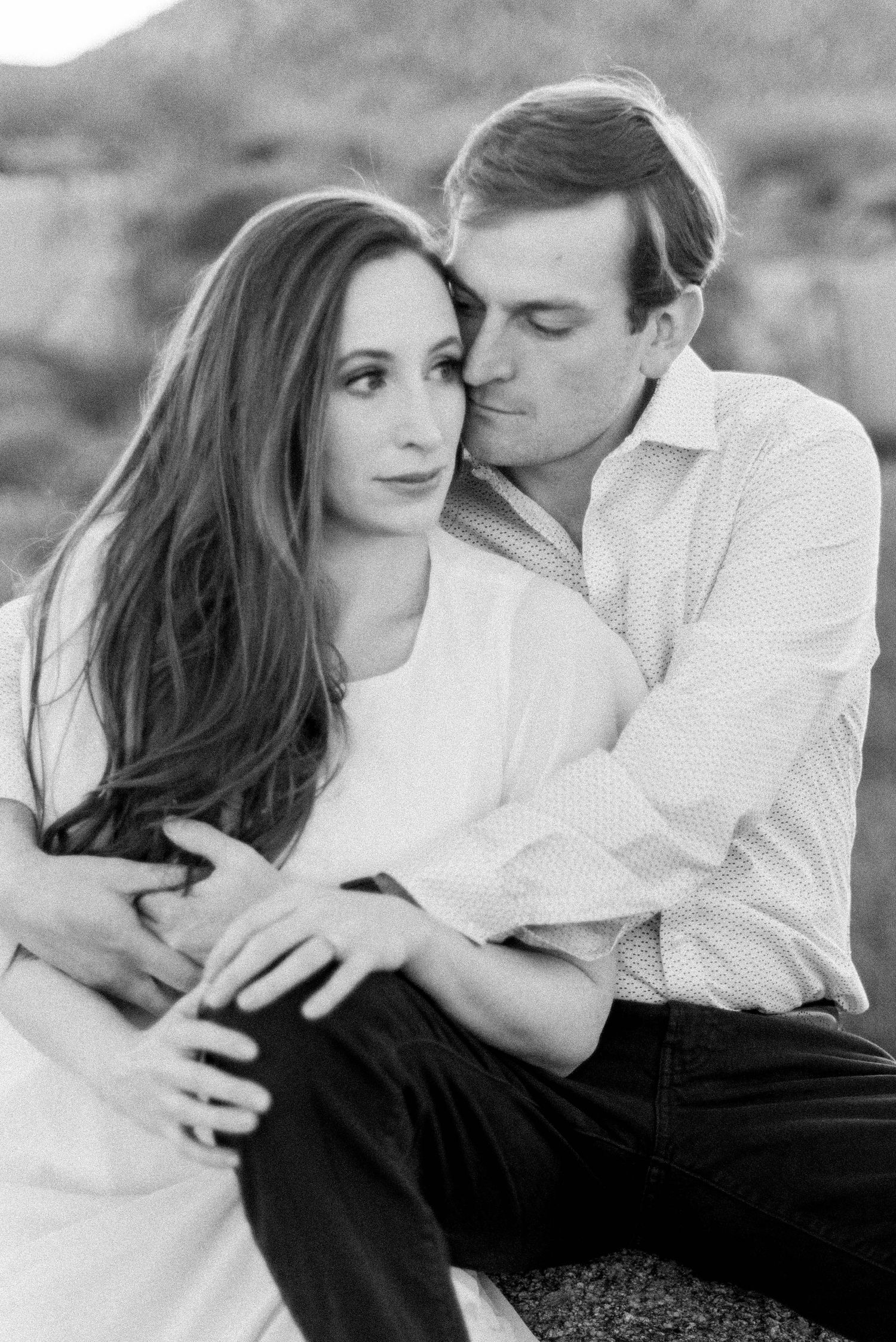 Black and white romantic engagement photos showing a couple embracing in an intimate outdoor portrait session.