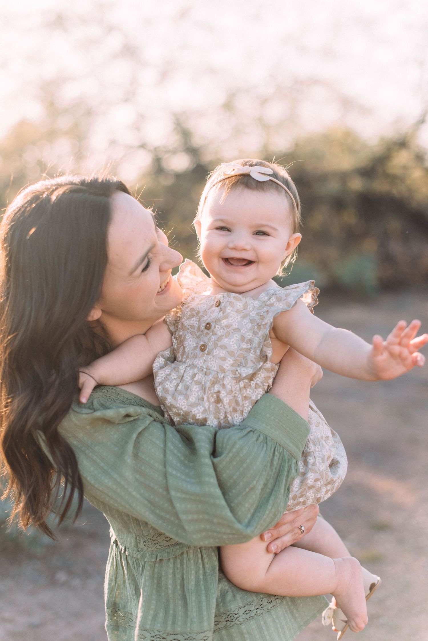 Joyful moment between mother and baby outdoors during golden hour.
