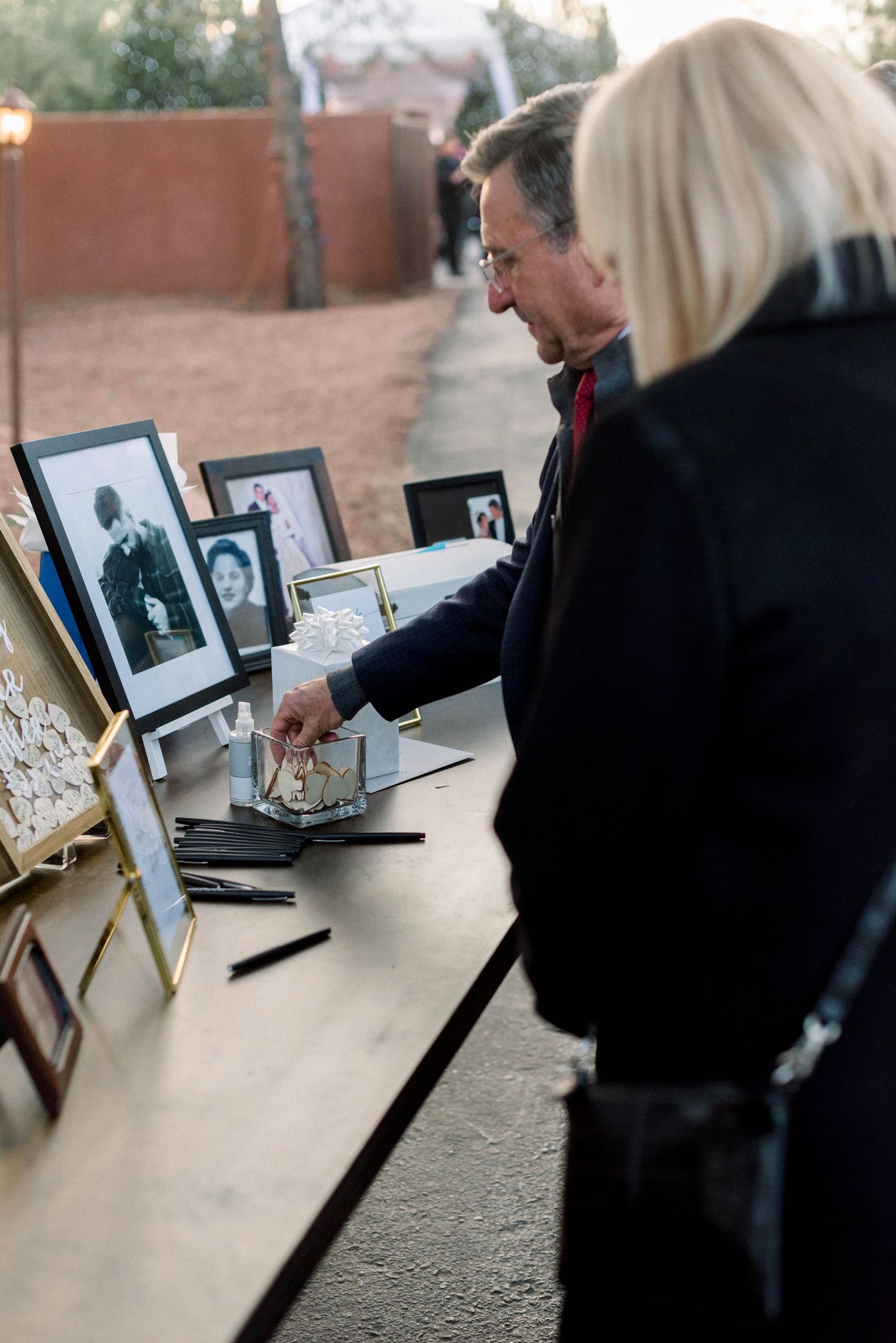 Guests viewing displayed photographs at wedding memory table.