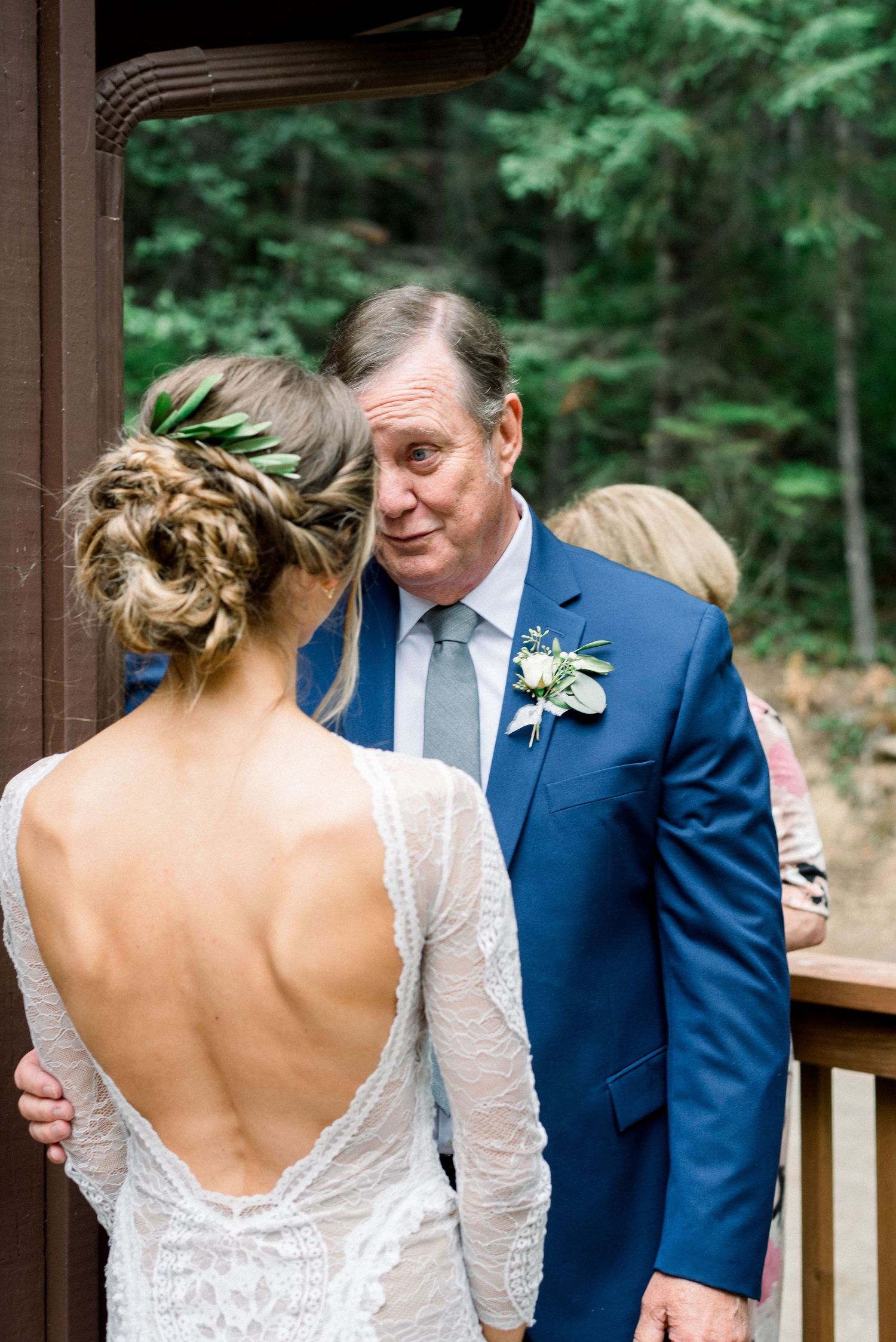 Intimate moment during a wedding with elegant backless lace dress and blue suit.