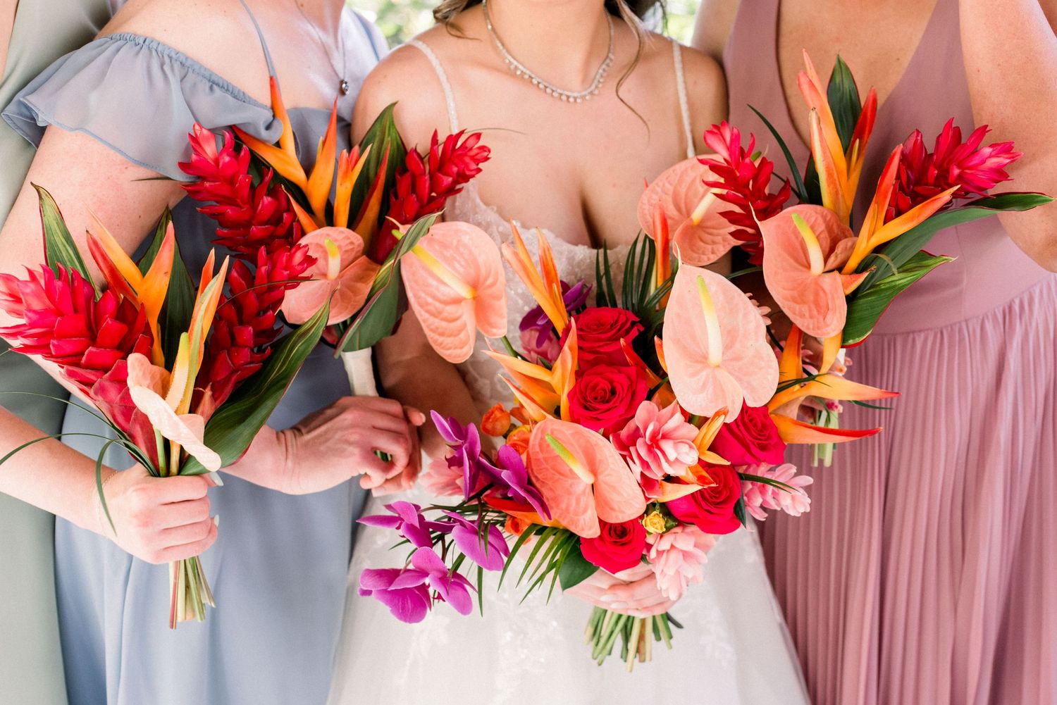 Vibrant tropical wedding bouquets featuring birds of paradise, orchids, and red flowers.