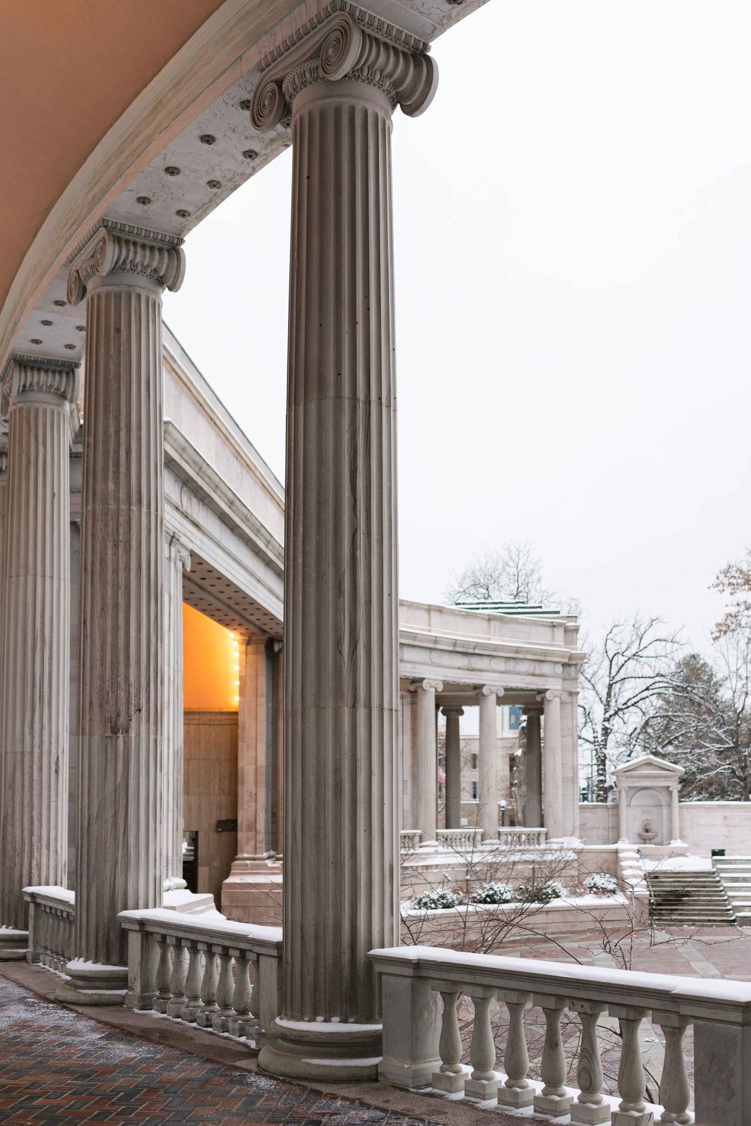 Classical white stone columns with ornate architectural details covered in snow.