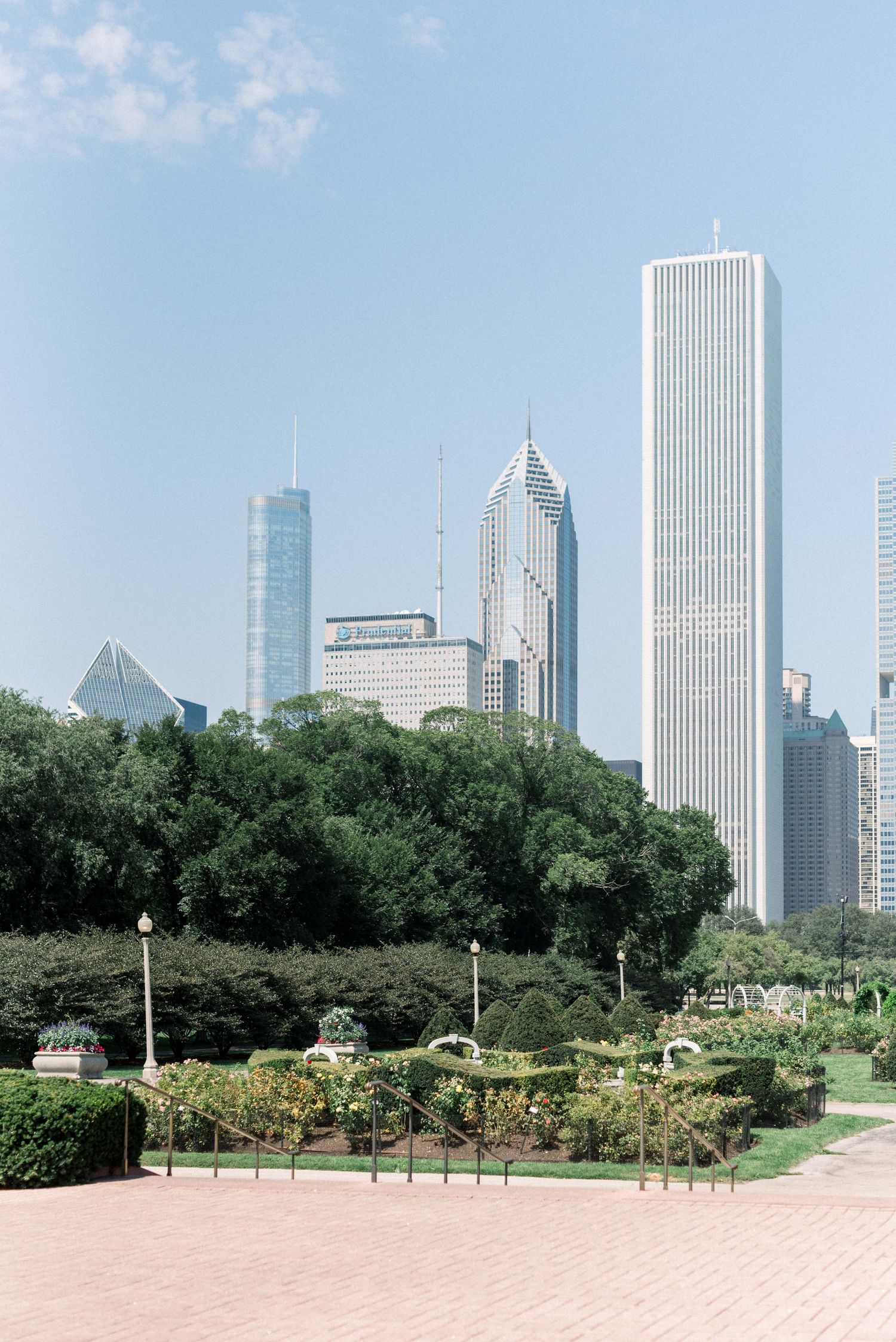 Chicago skyline view from Grant Park with lush greenery in the foreground.