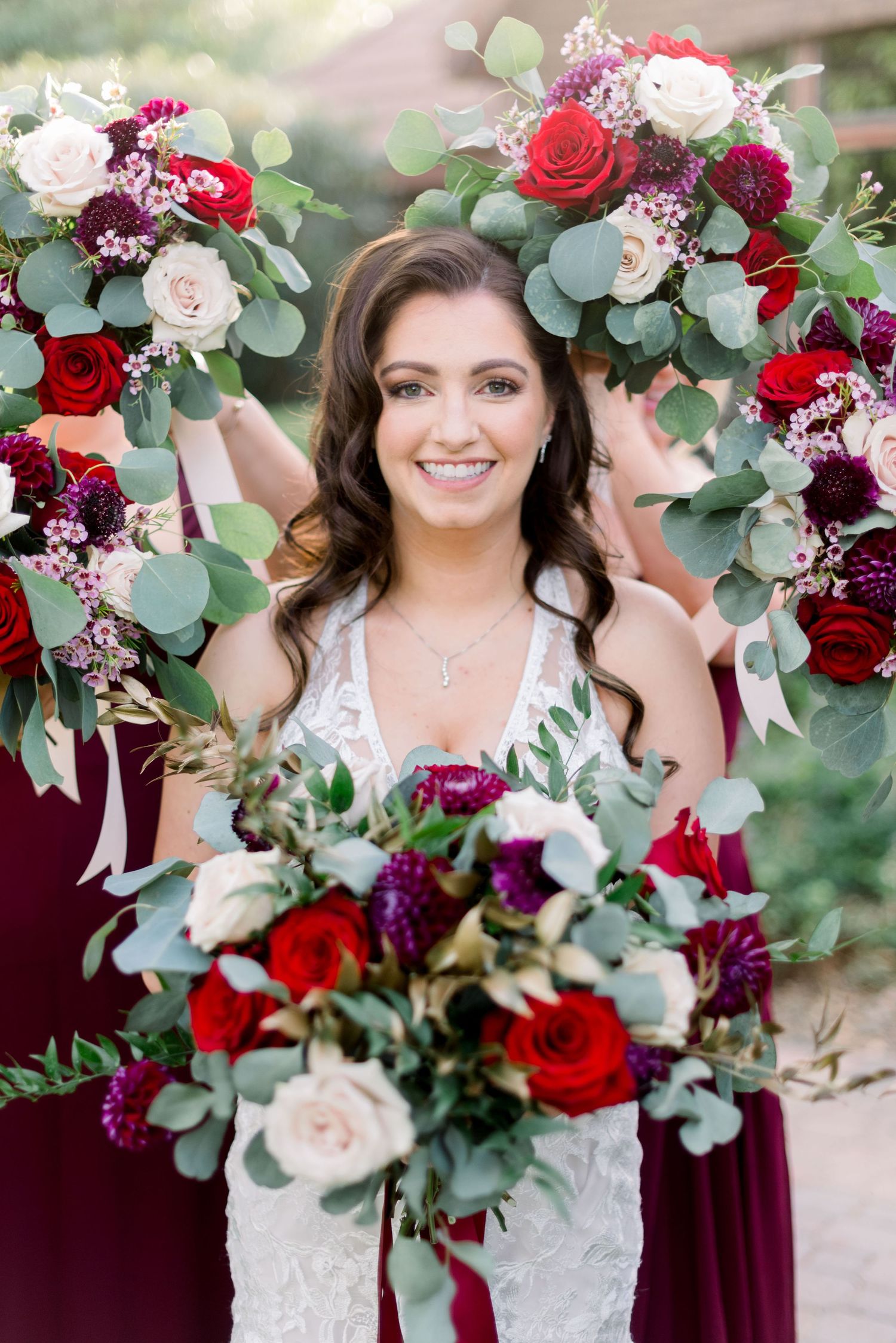 Beautiful bridal portrait surrounded by red and burgundy floral arrangements with eucalyptus.