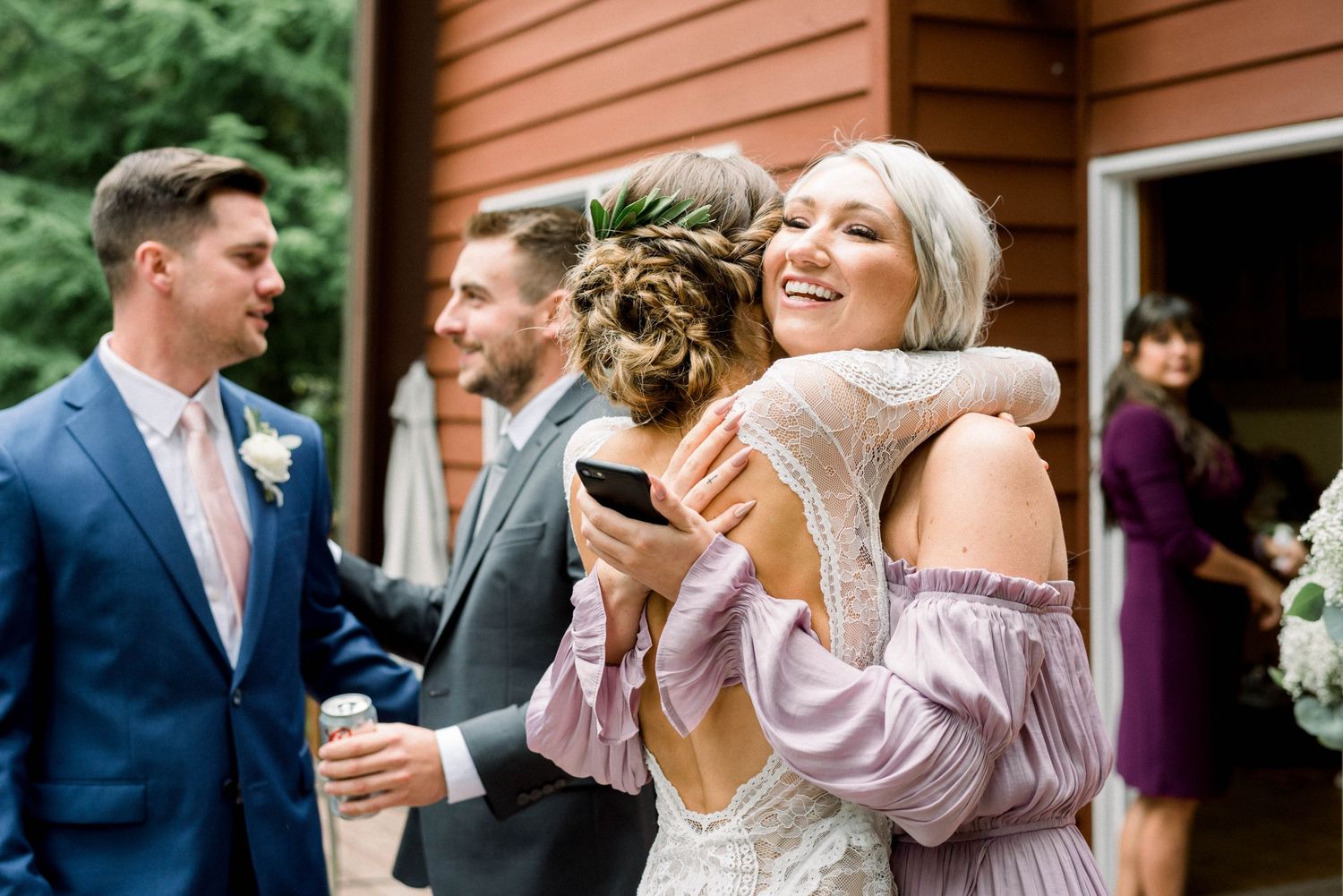 Wedding guests share joyful hugs and laughter during an outdoor celebration.
