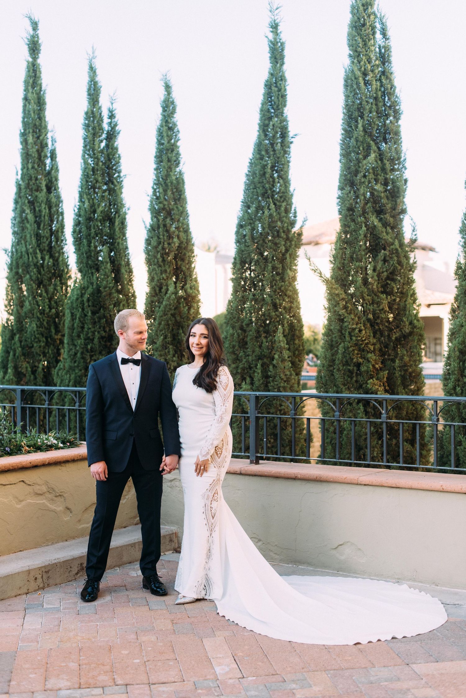 Wedding portrait with tall cypress trees in background and bride's train elegantly displayed.