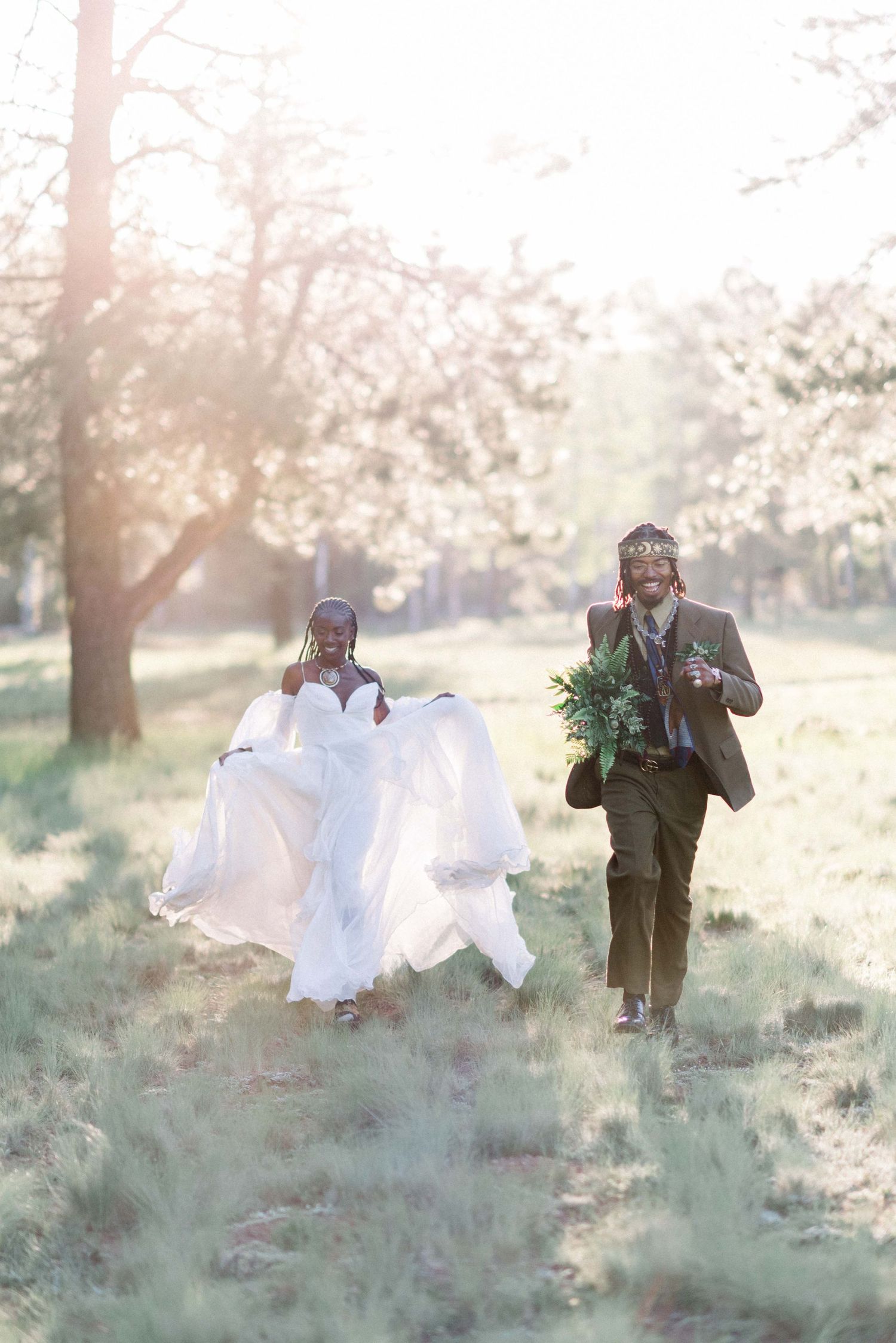 Ethereal wedding photo in a sunlit field with flowing white dress and natural surroundings.