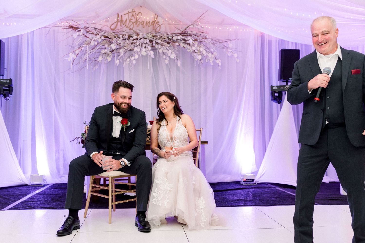 Wedding reception entertainment with guests performing in a beautifully decorated white tent space.