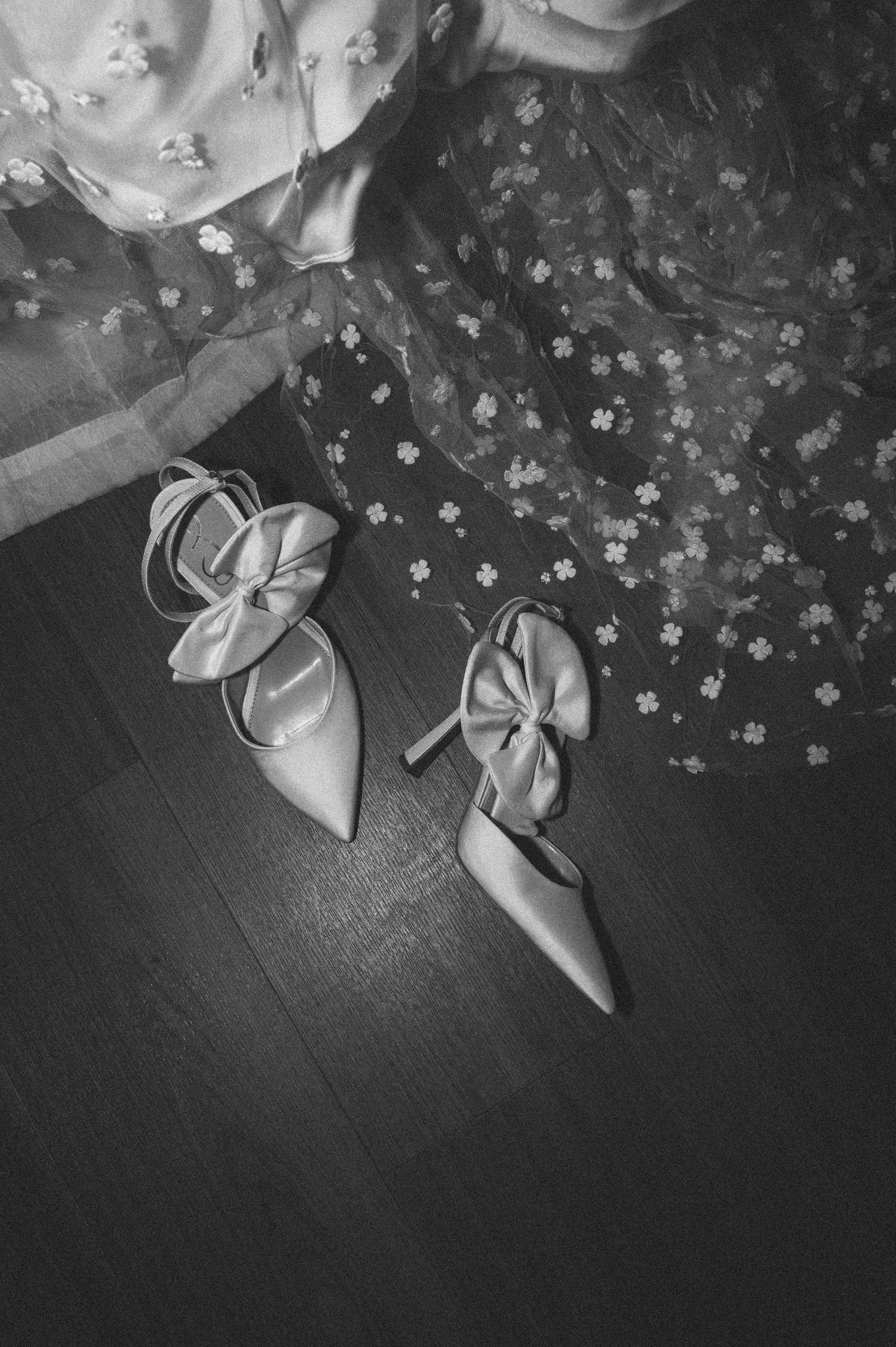 Elegant wedding shoes and floral details arranged in black and white.