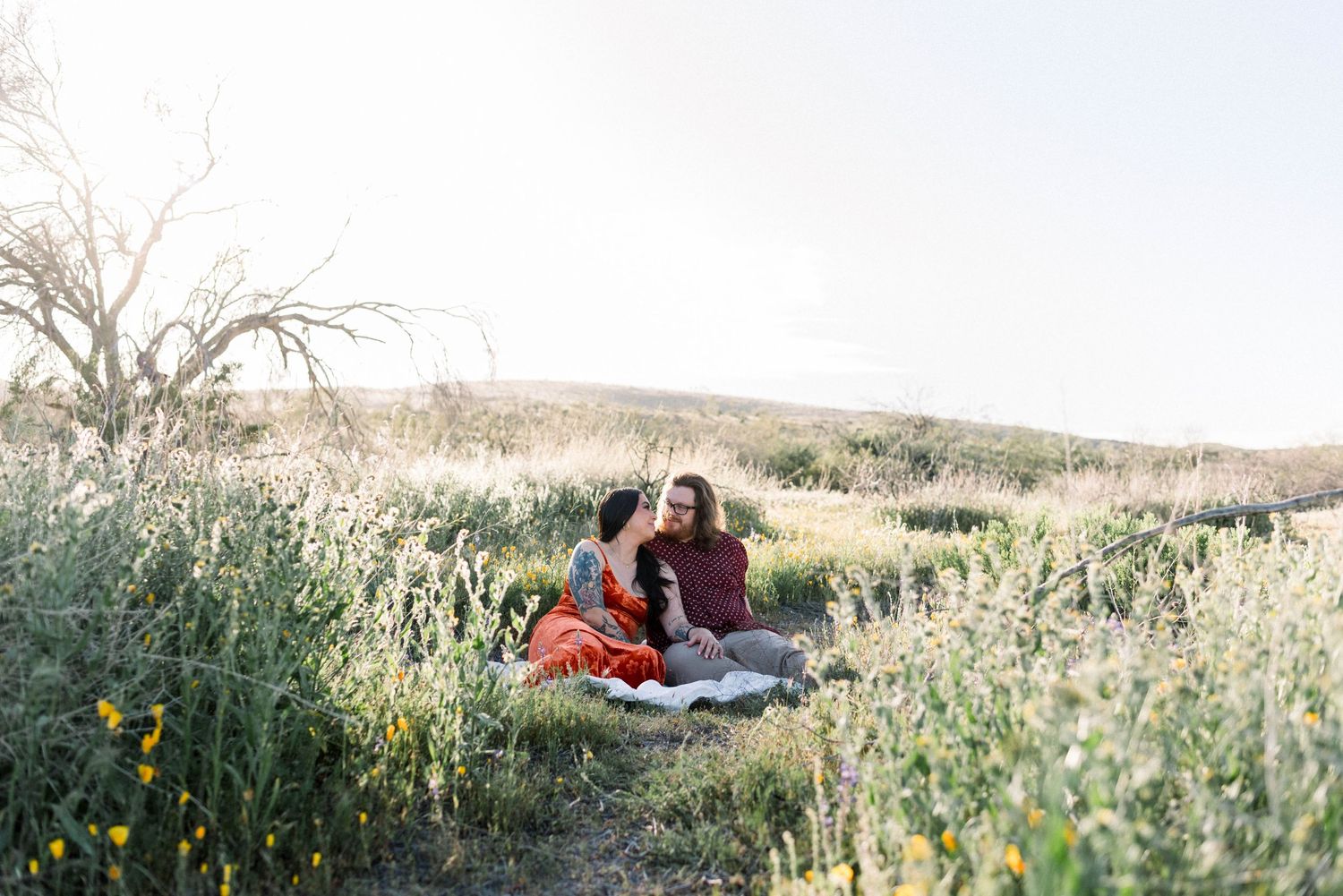 People relax in a scenic wildflower meadow on a sunny afternoon with rolling hills in the background.