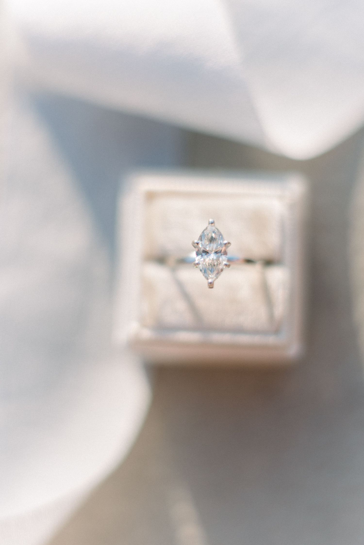 A stunning marquise diamond engagement ring displayed in a light gray ring box.