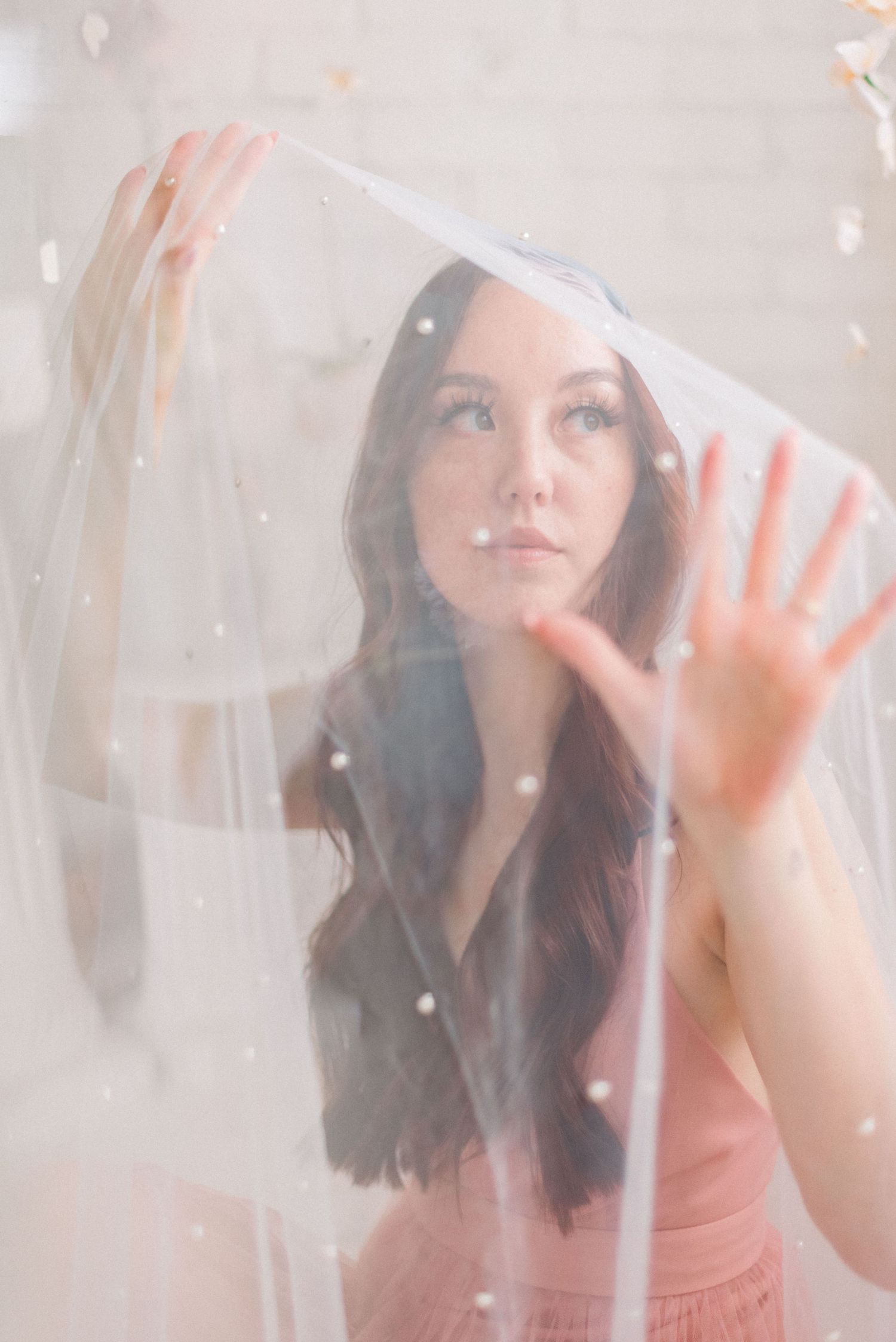 Ethereal portrait through sheer veil with soft lighting and delicate details.