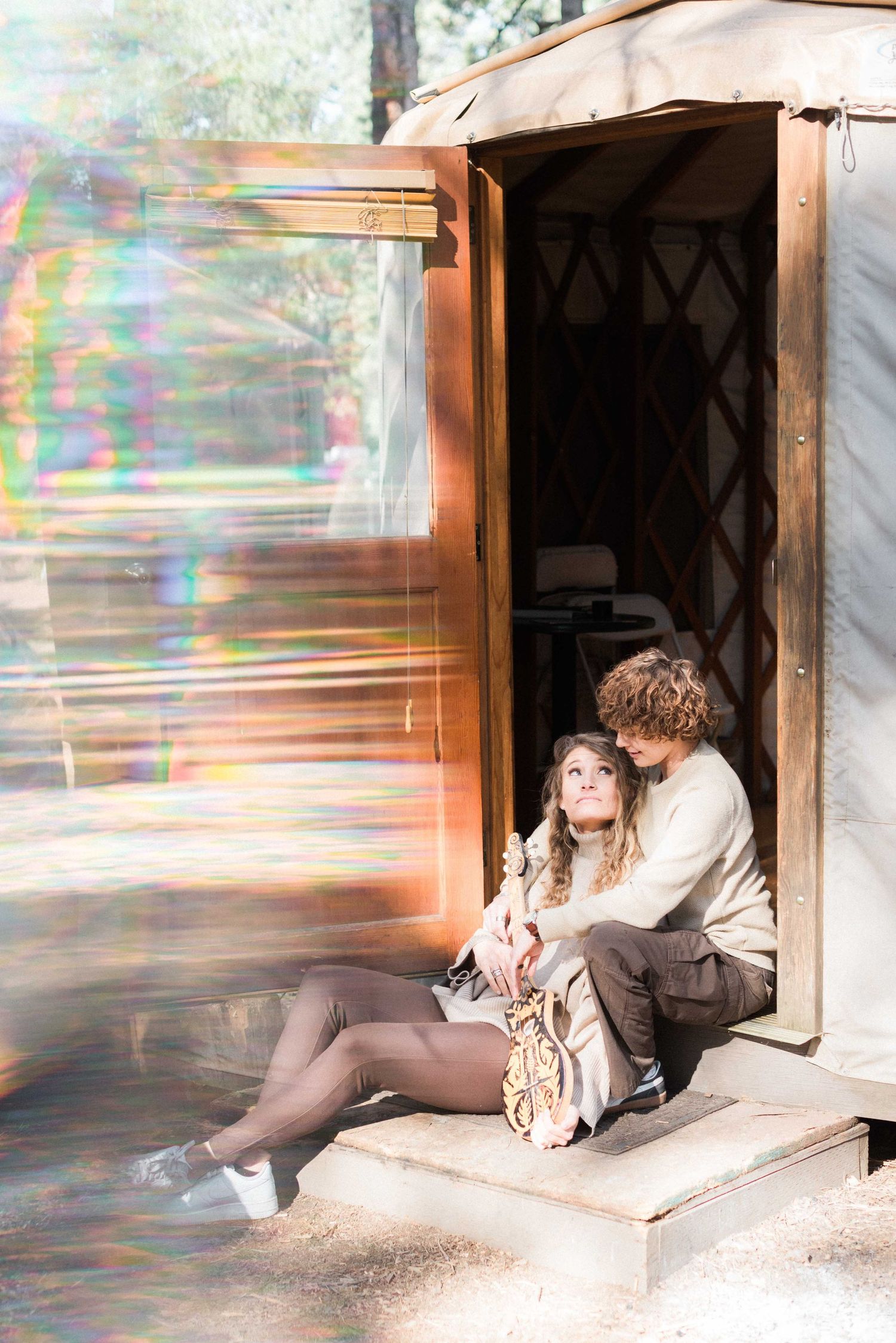 Intimate moment captured with rainbow light effect at yurt entrance.
