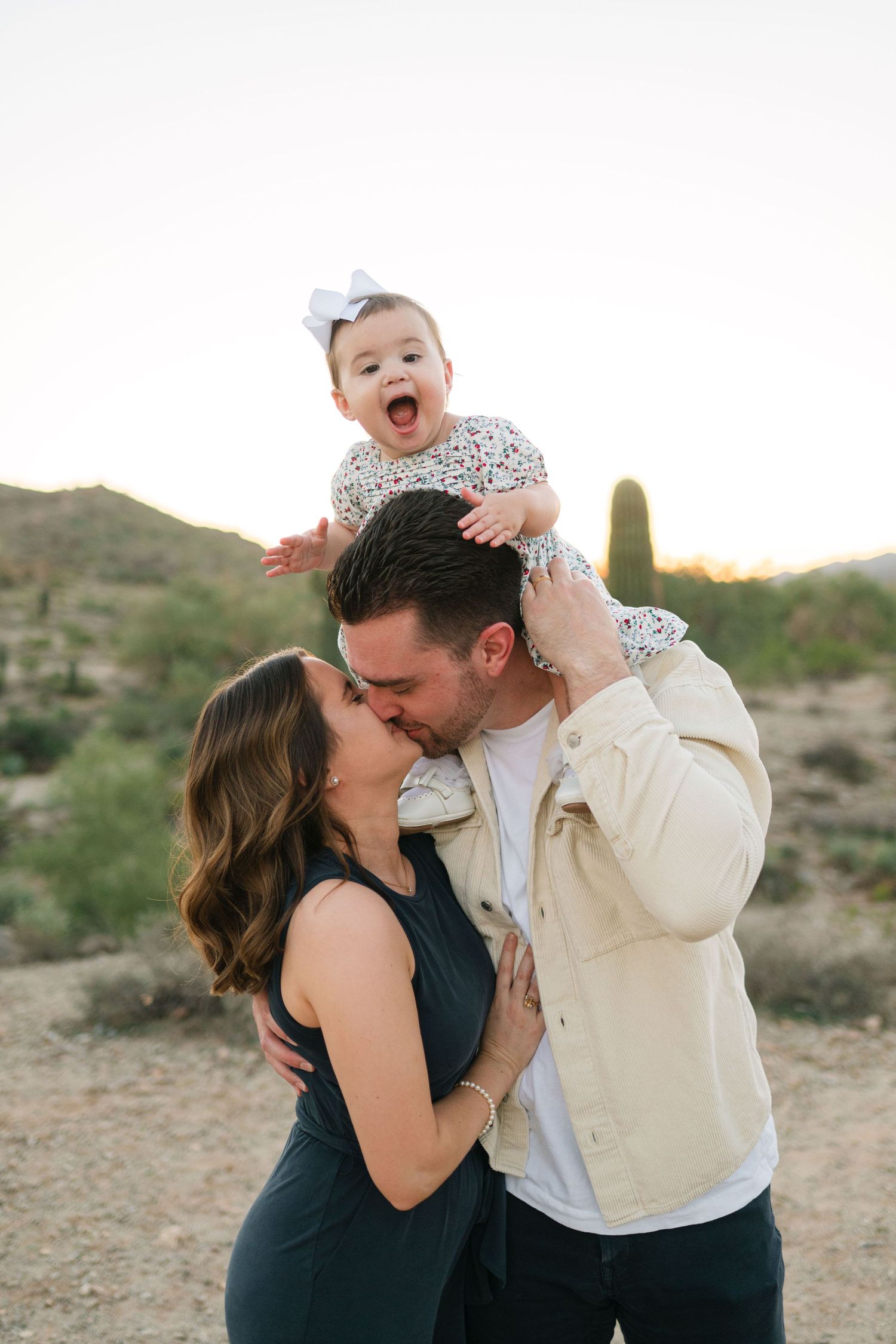A loving family shares tender moments together against a desert landscape at sunset.