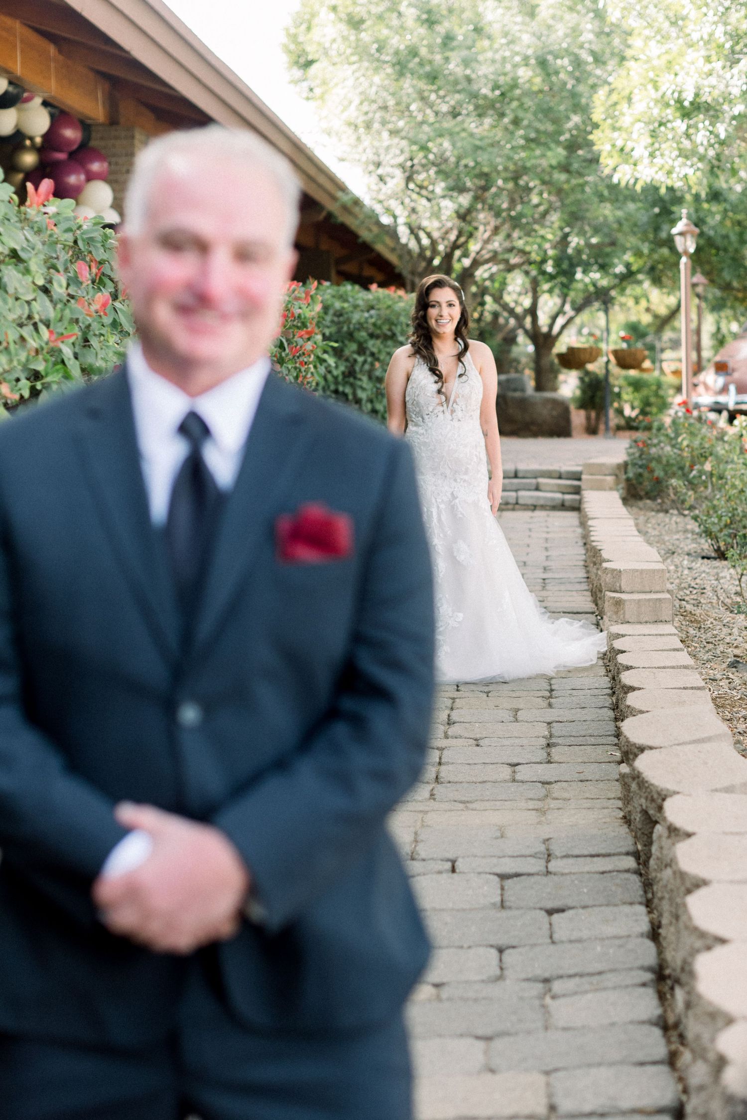 Outdoor first look wedding moment on stone pathway with garden backdrop.