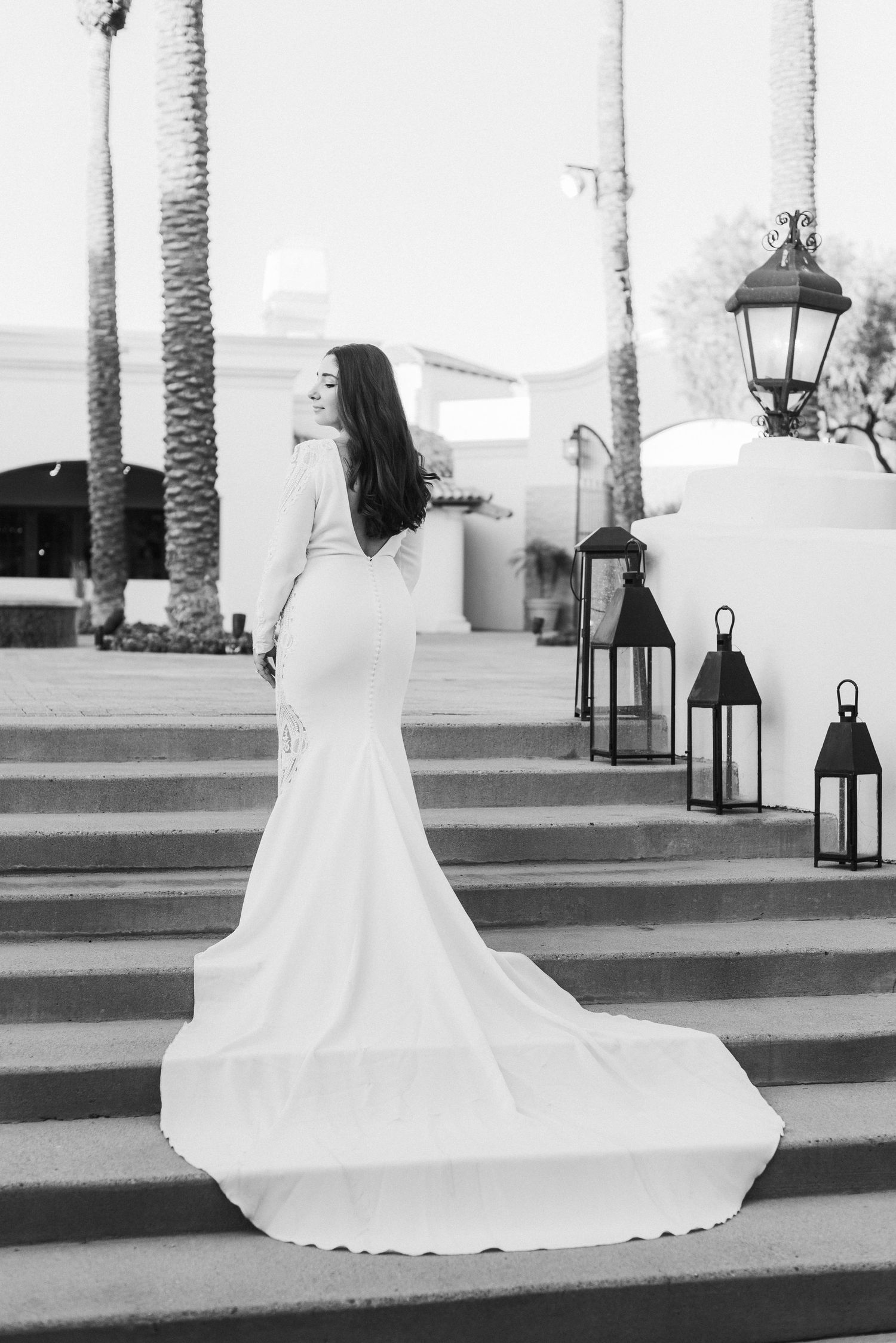 A dramatic black and white photo of a wedding dress with flowing train on Mediterranean-style steps.