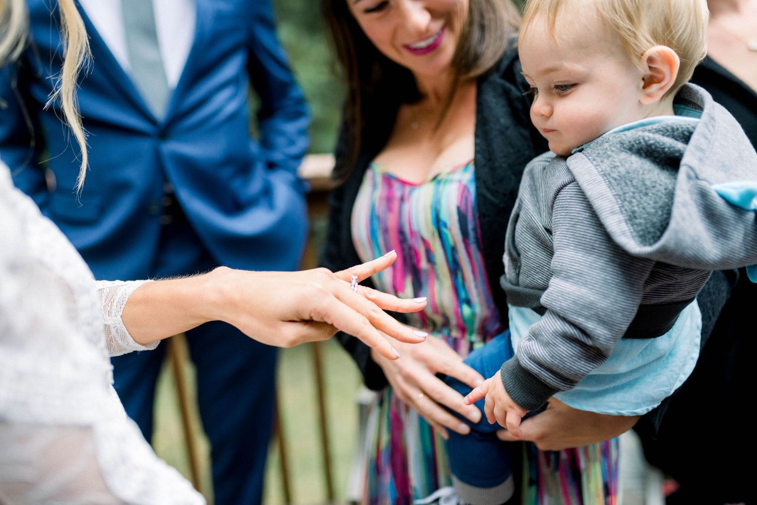 A close-up of wedding rings being shown during an outdoor celebration.