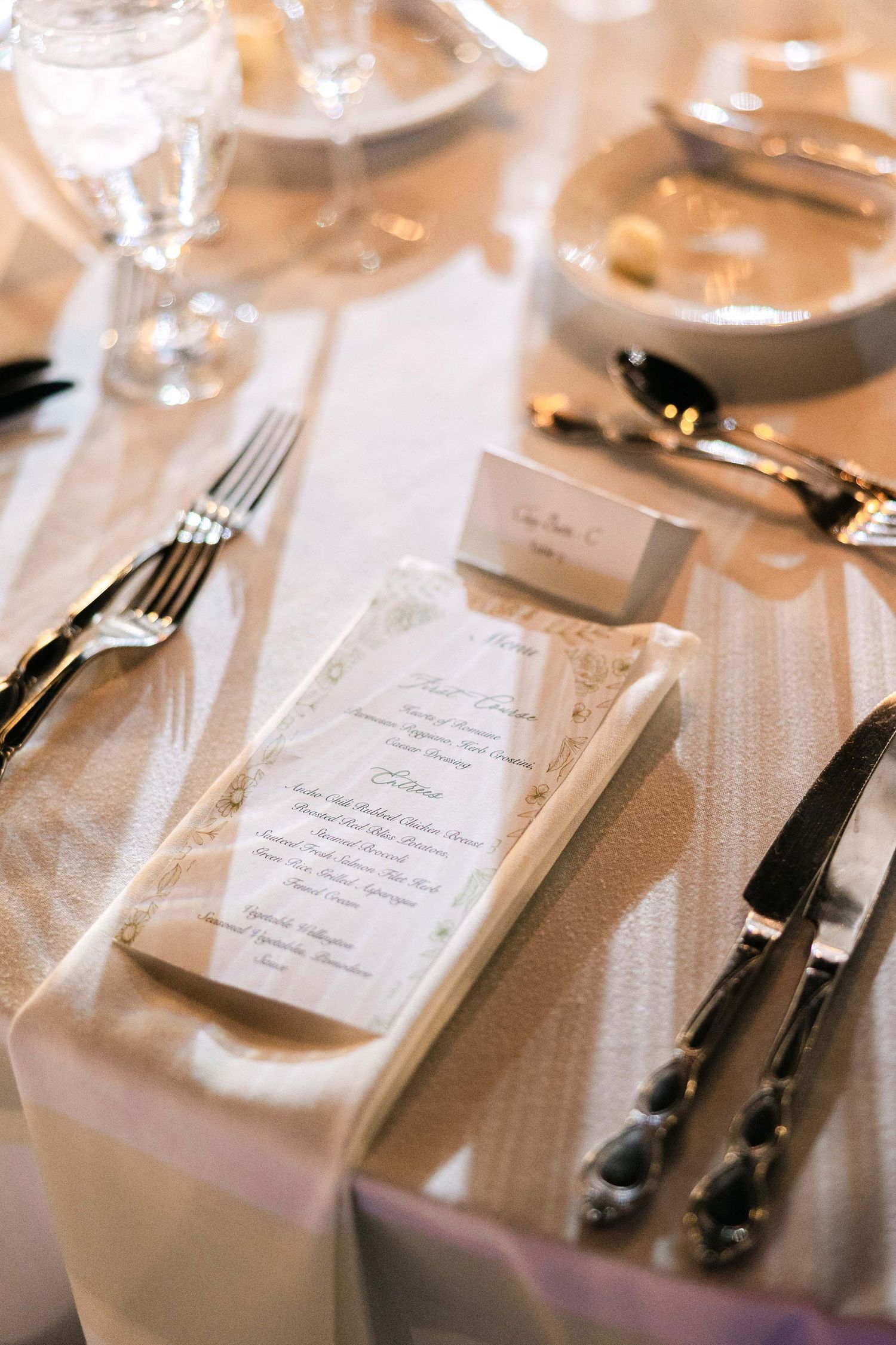 Elegant place settings with menu cards and silverware on white tablecloths.