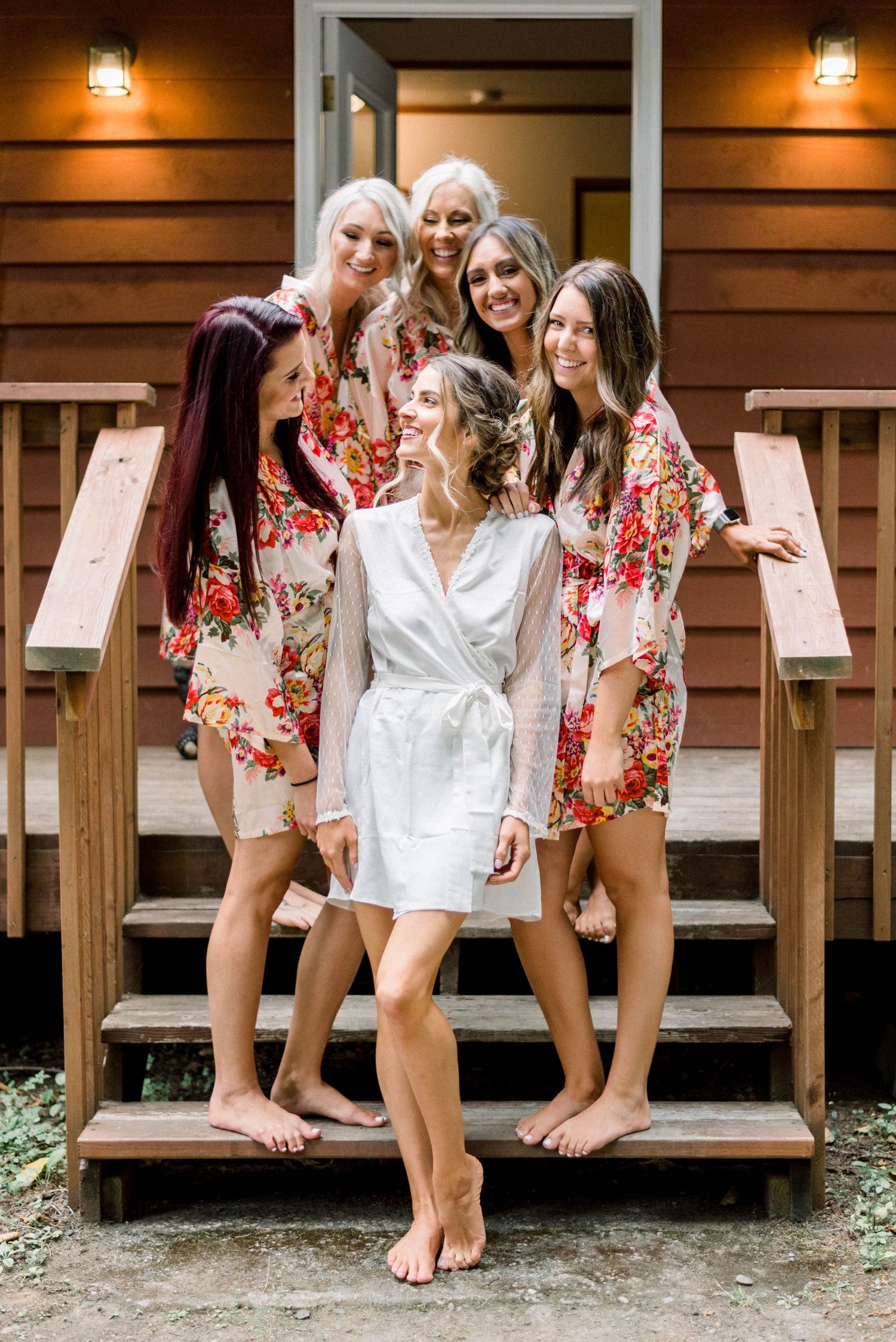 Group wearing floral robes poses on wooden cabin steps.