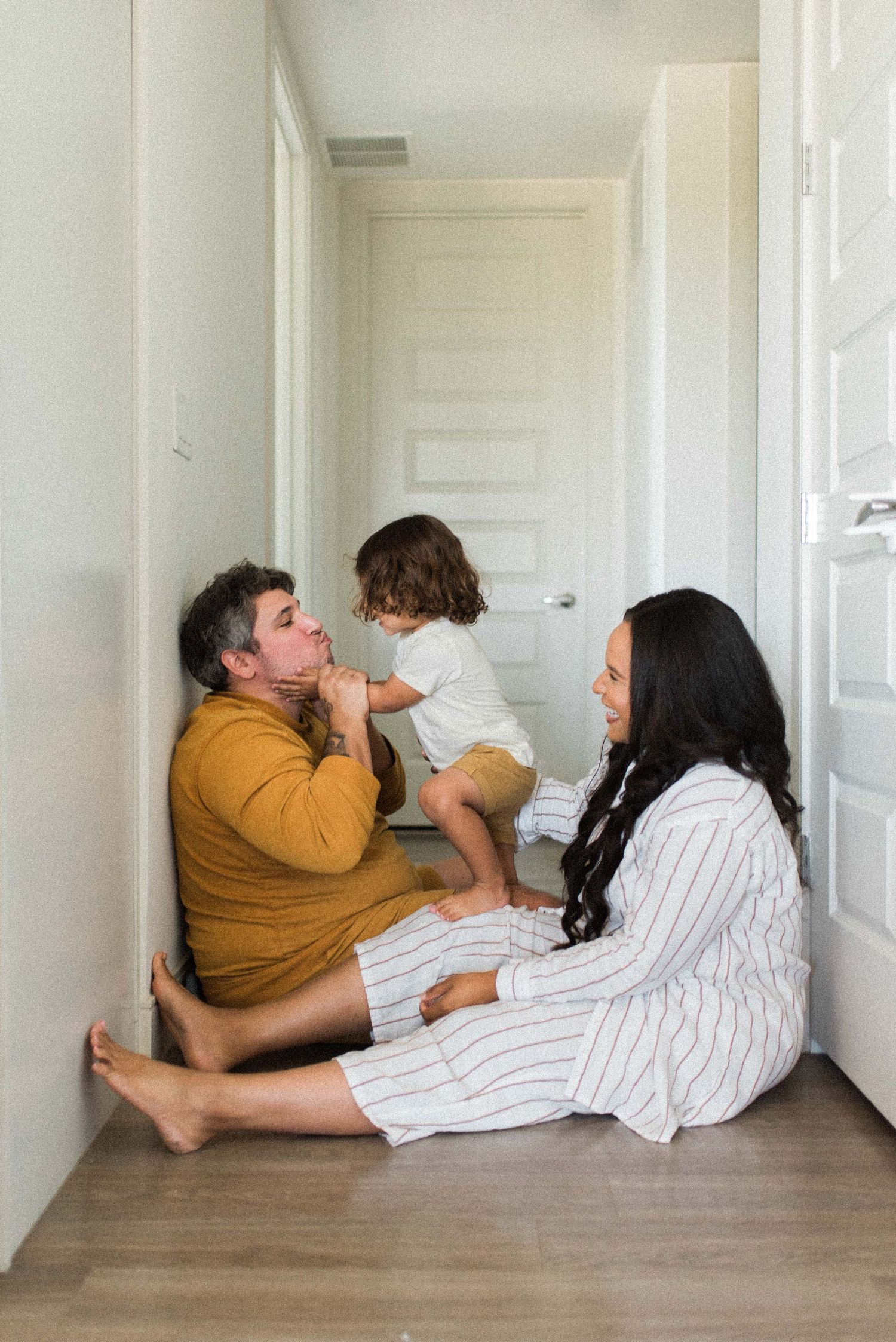 Family of 3 sitting in their hallway happy