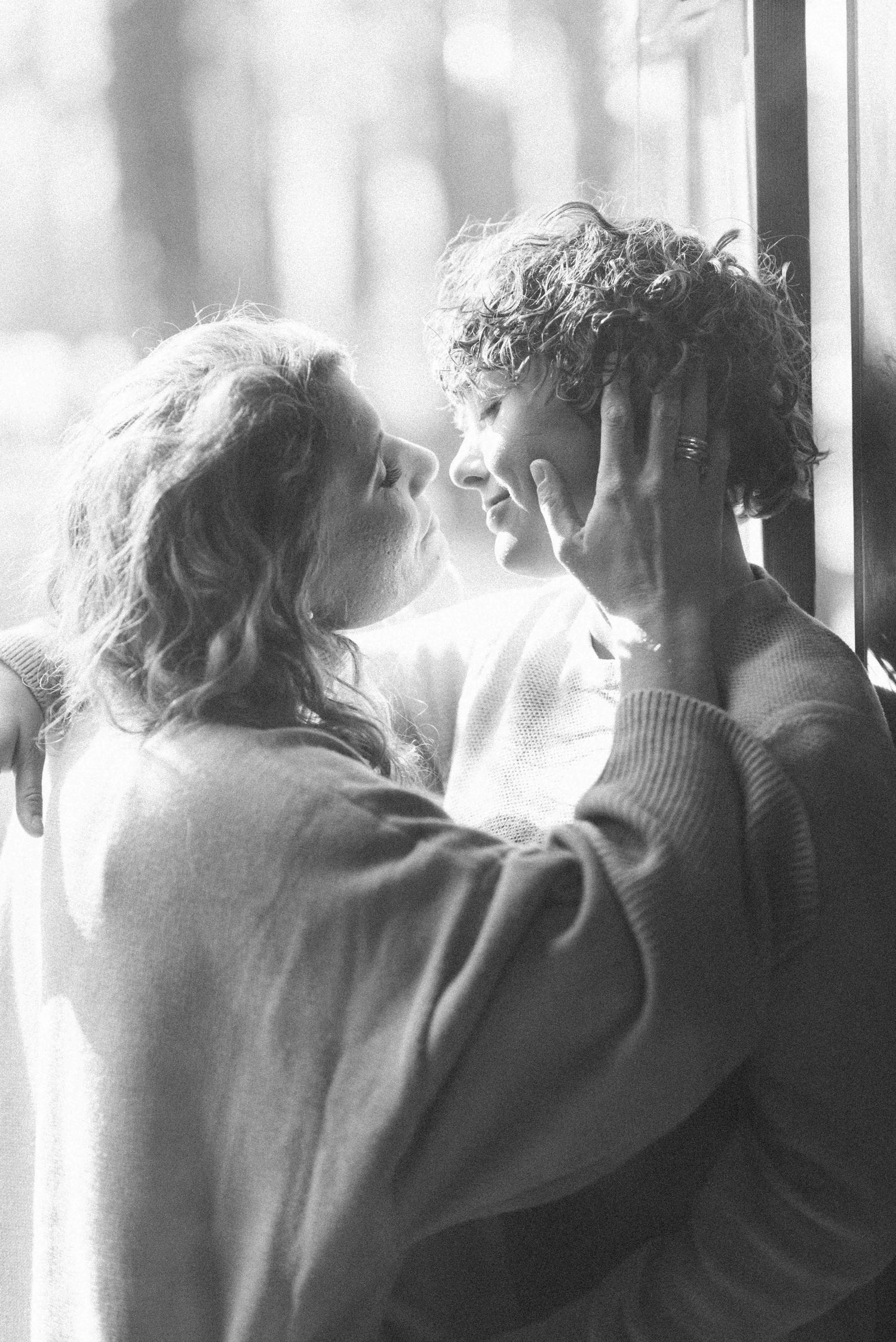 Intimate black and white portrait of couple in soft window light.