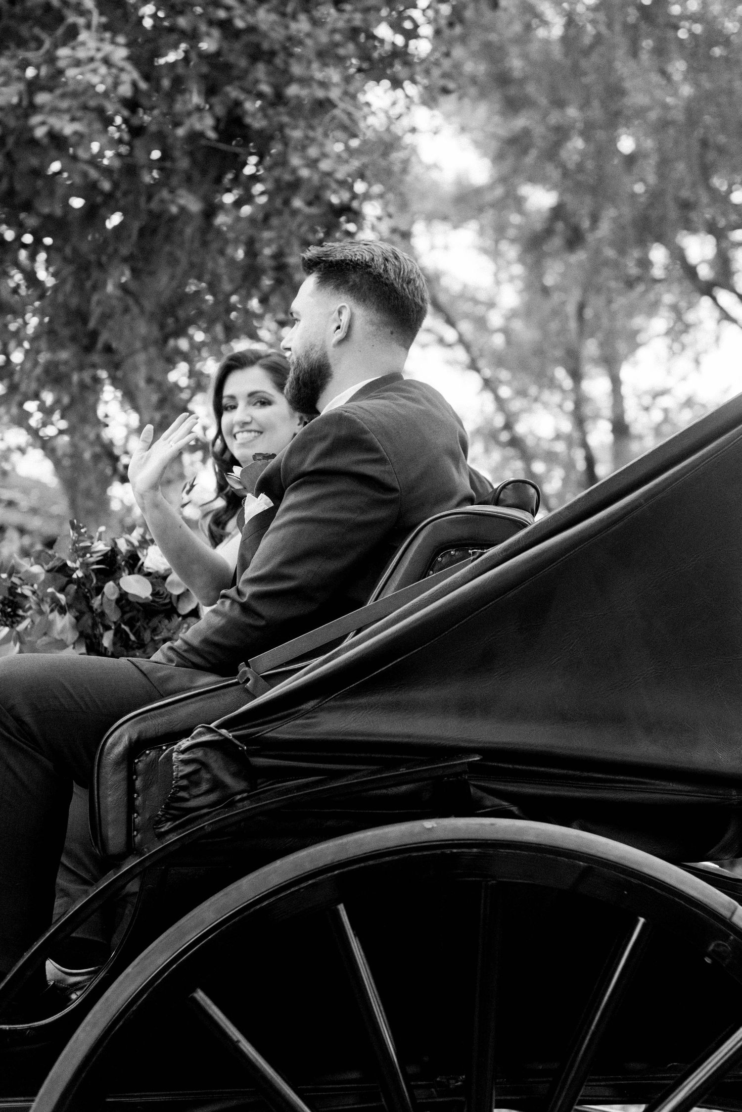 Black and white photo of couple enjoying their carriage ride through the park.