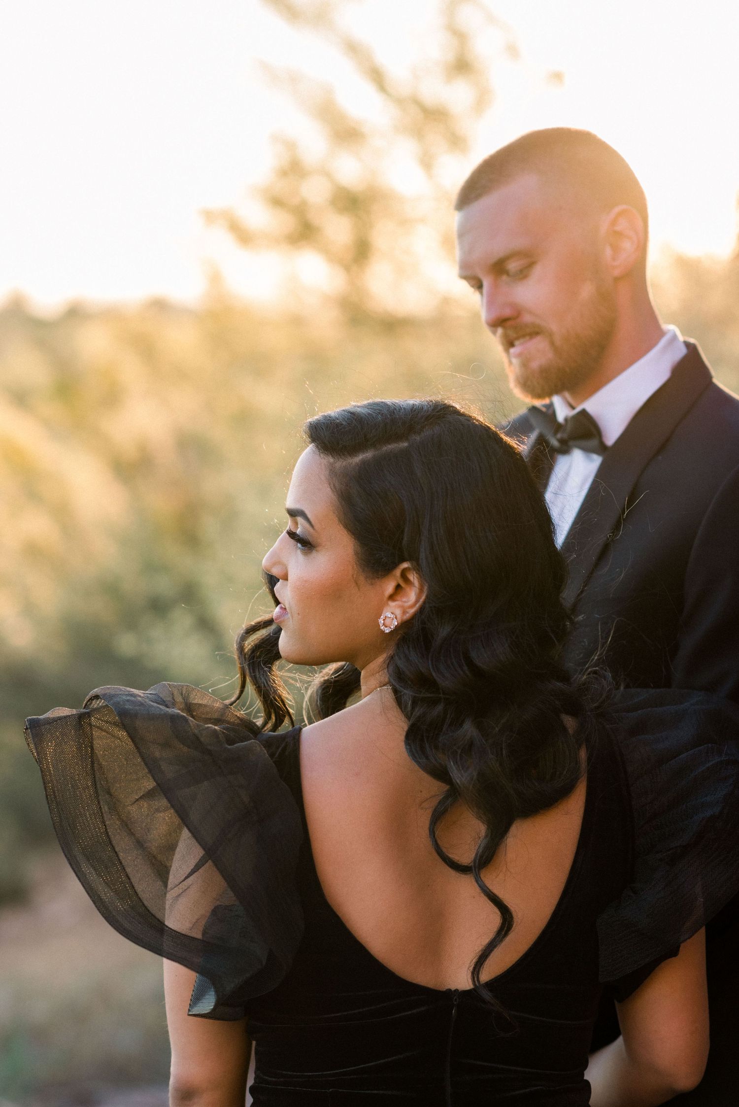 Romantic sunset portrait of couple in black formal wear.
