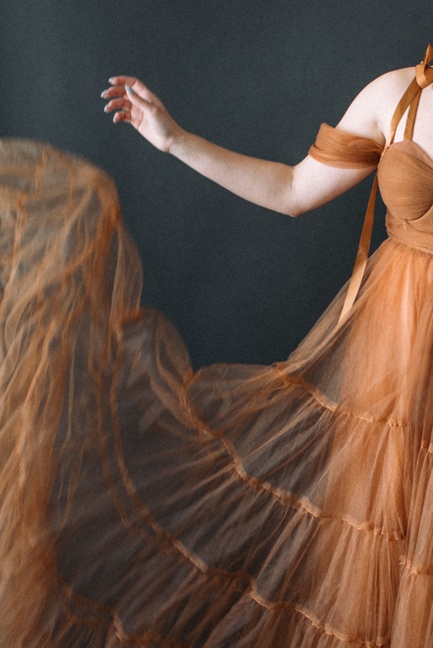 A flowing peach-colored dress twirls gracefully in motion against a dark background, creating an ethereal movement effect.