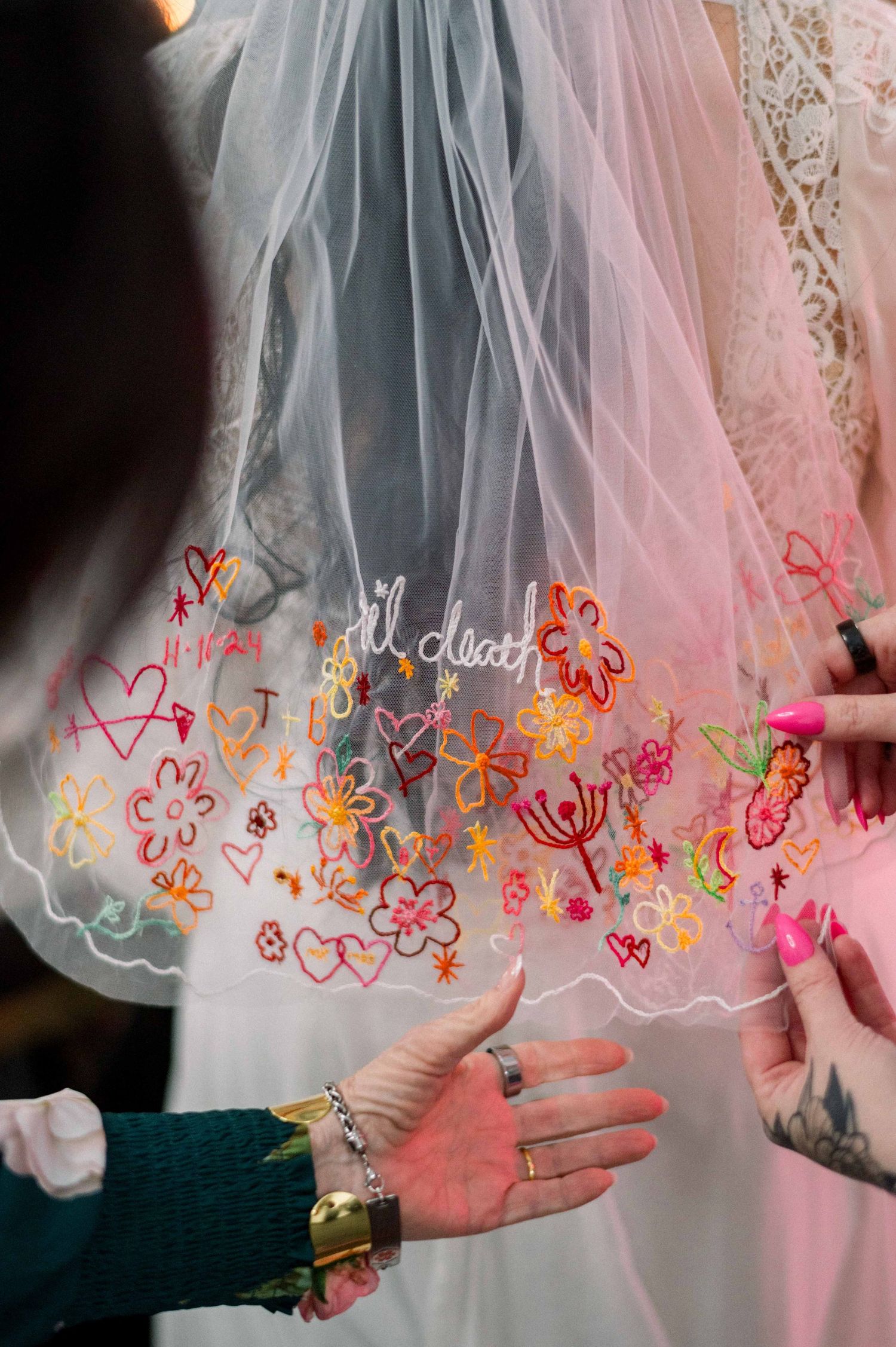 Wedding veil with colorful embroidered flowers and hearts along the hem.
