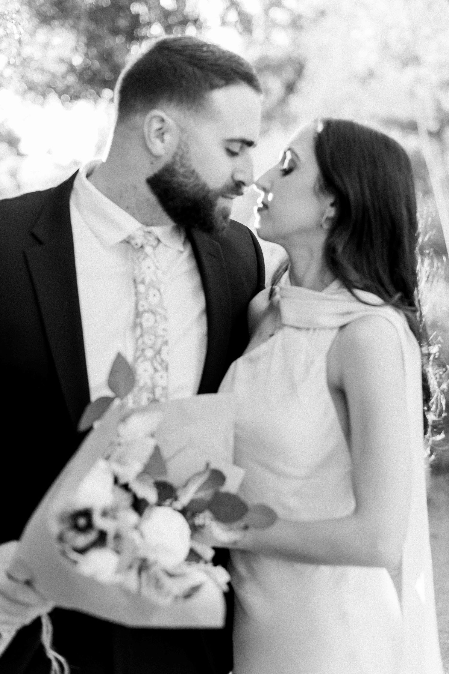 A romantic black and white photo series showing a bride and groom sharing intimate kisses while holding a bouquet.