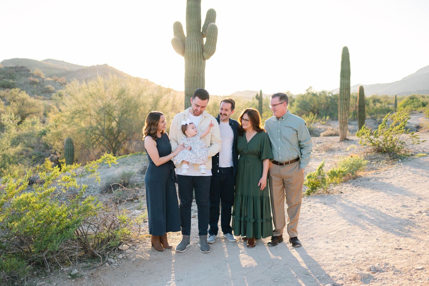 Group portrait session in a desert landscape with saguaro cactus and mountains during golden hour.