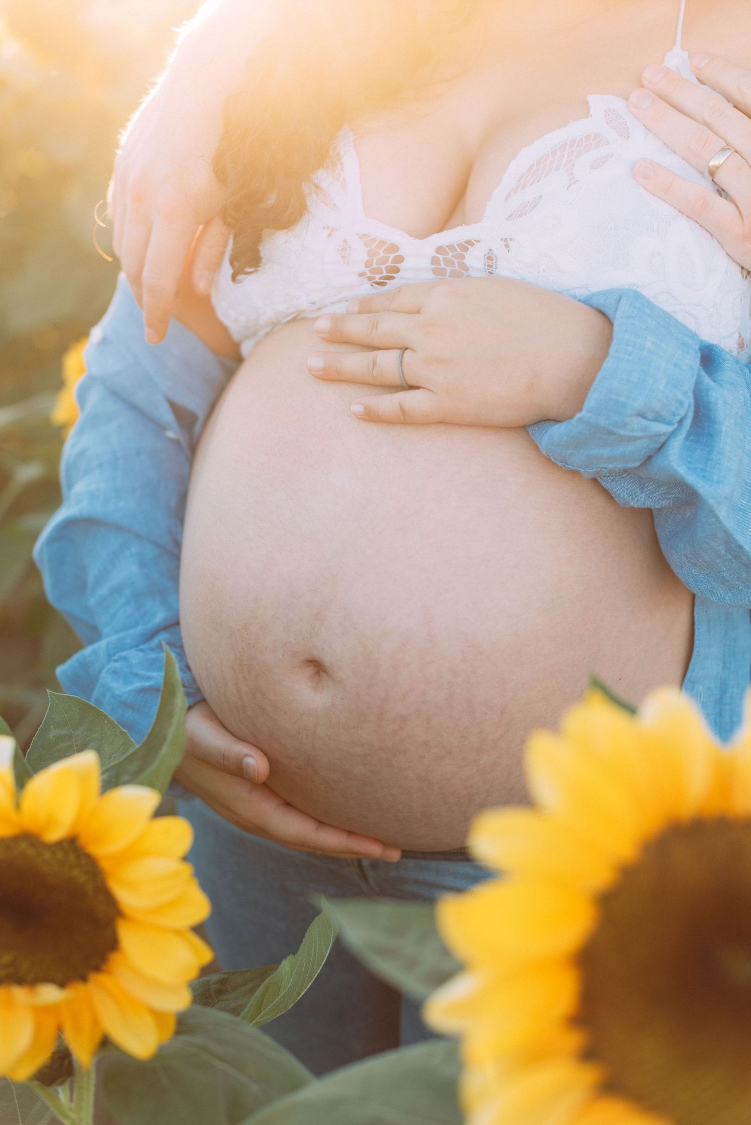 Close up of pregnant belly in sunflower field
