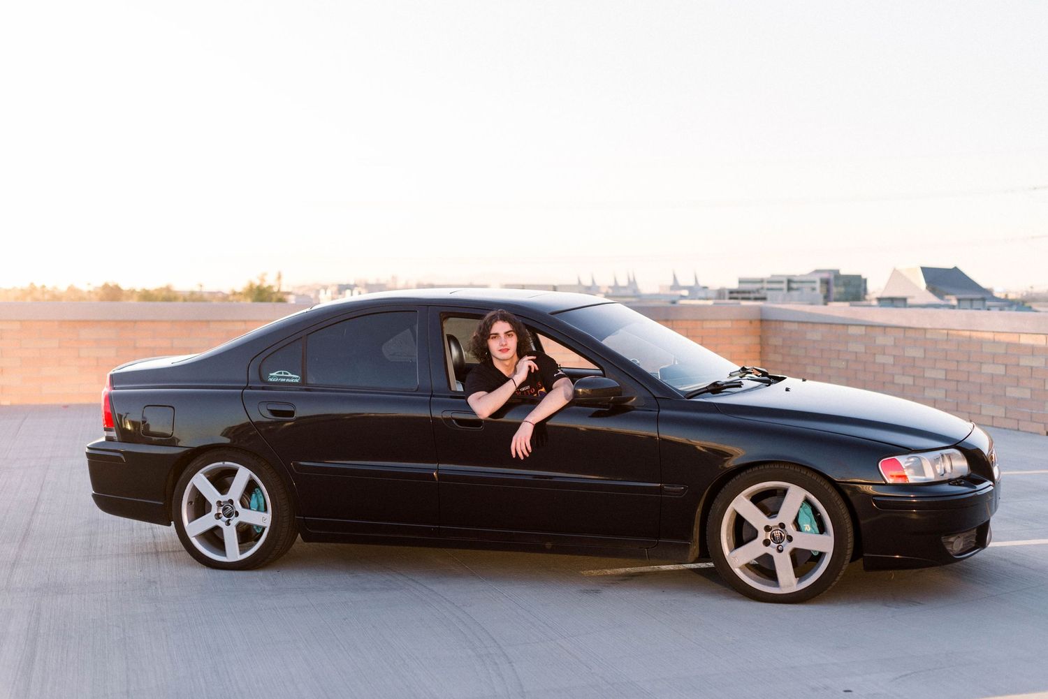 Black sedan car parked in desert location during sunset.