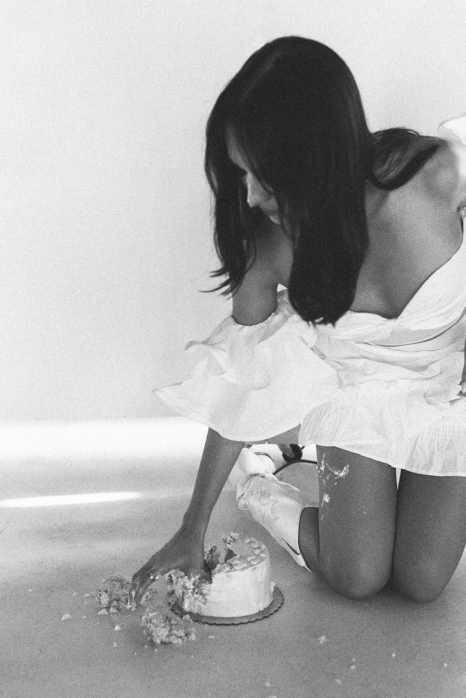Person in white dress kneeling beside scattered sparkles and decorations in black and white photo.