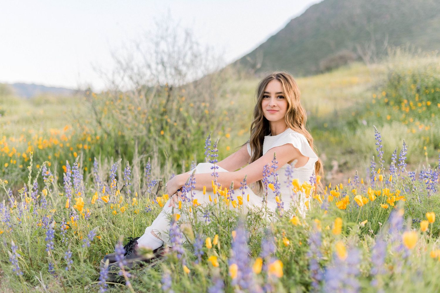 A spring portrait surrounded by blooming wildflowers on a mountainside at sunset.