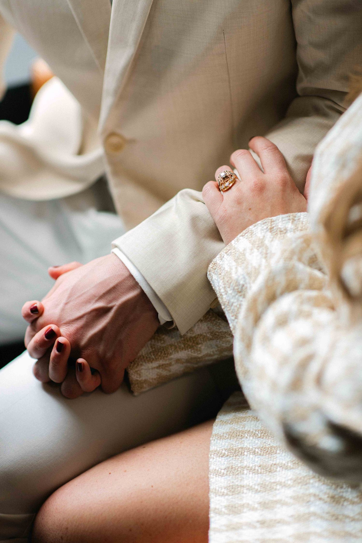 Close-up of couple's hands intertwined during romantic moment showing wedding ring details.