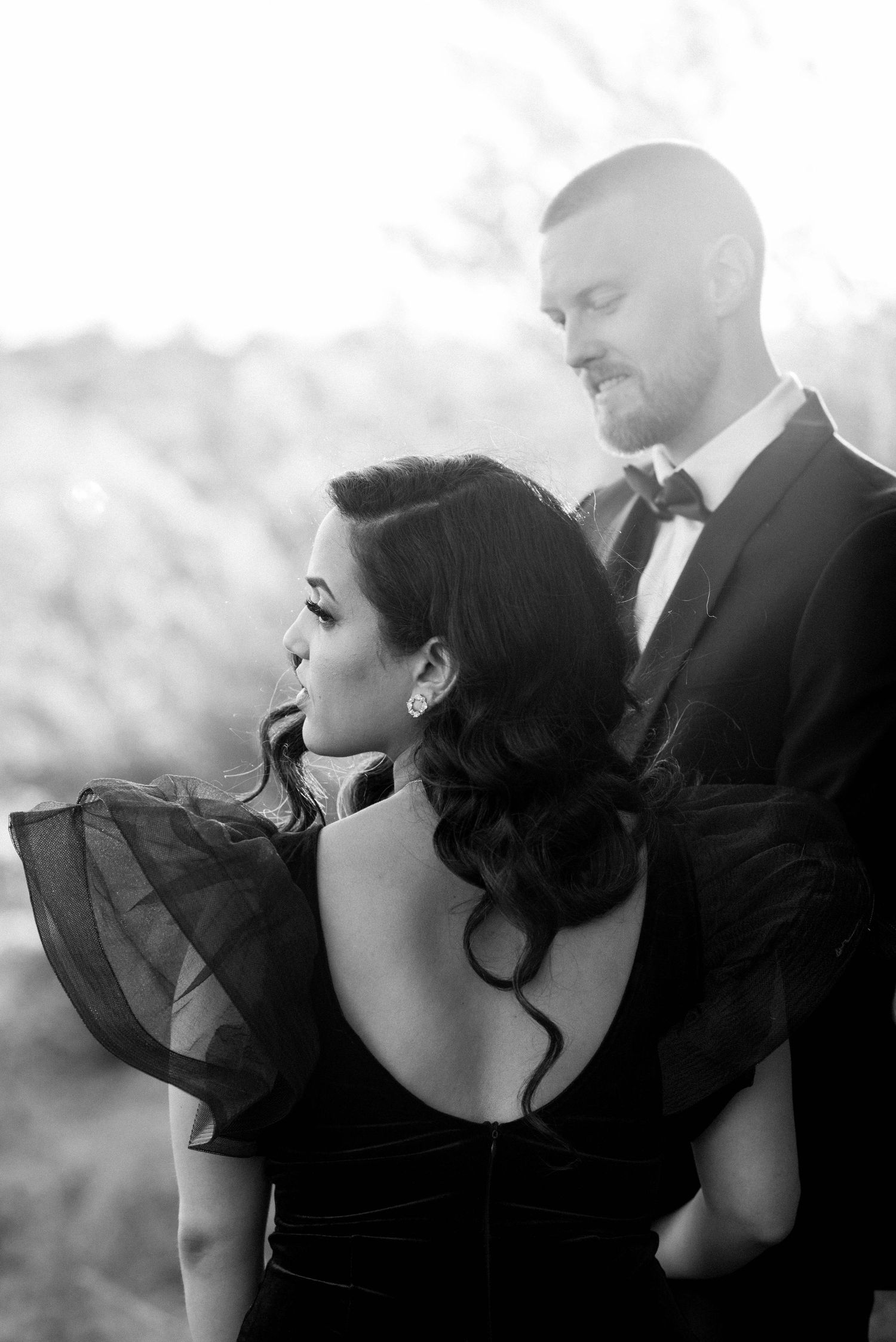 Dramatic black and white portrait of couple in formal wear at sunset.