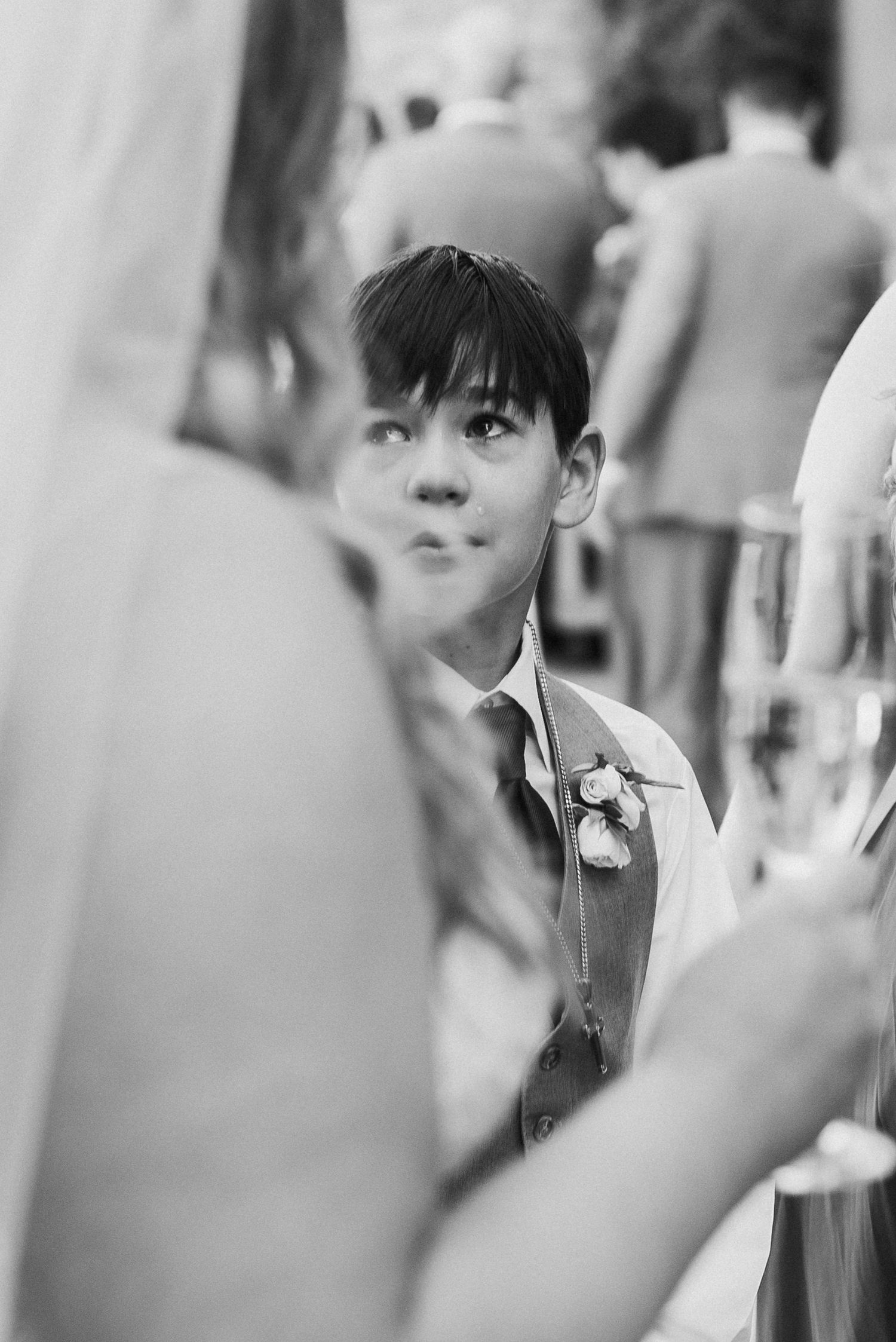 Black and white candid wedding moment captured through a crowd.