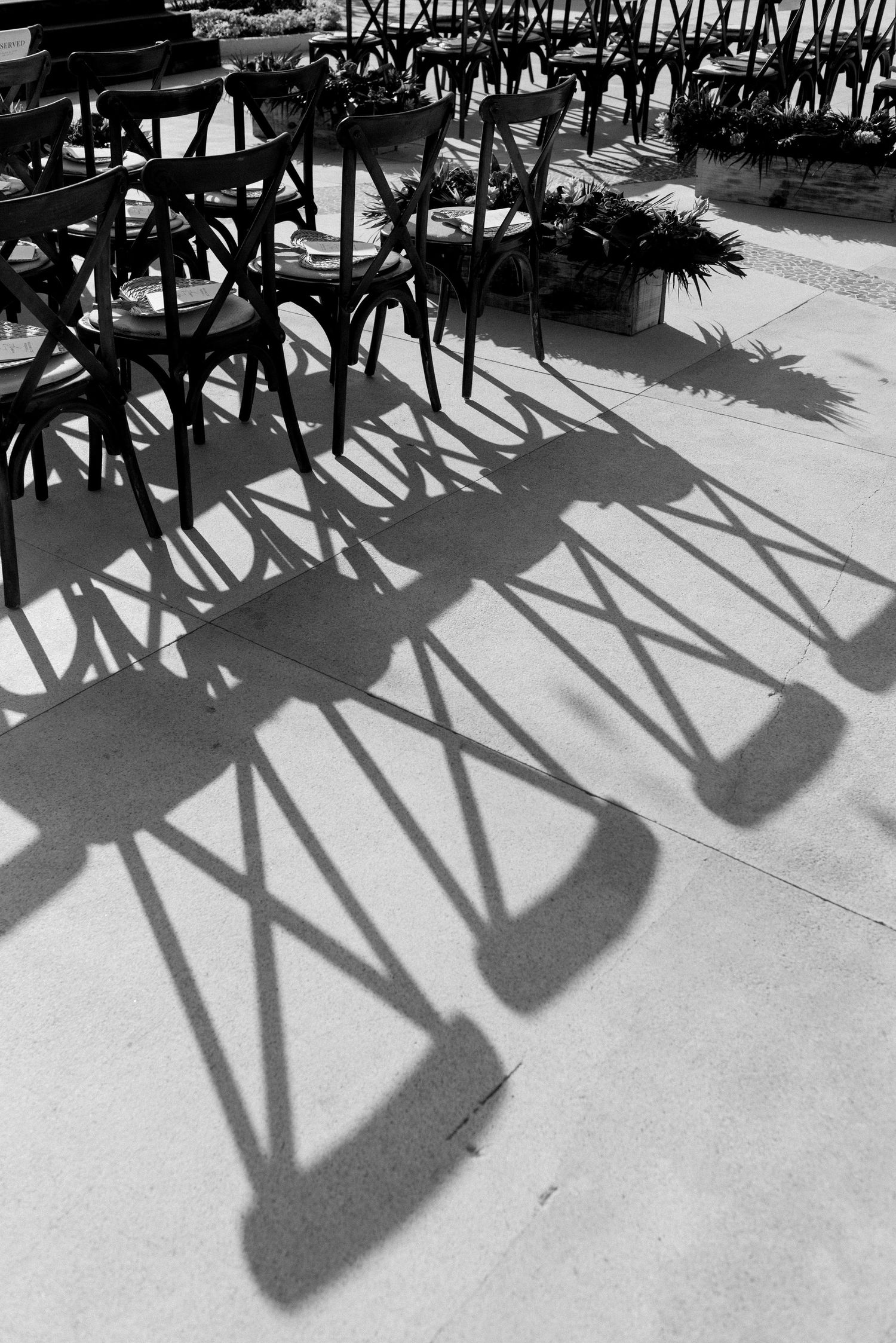 Dramatic black and white photo of wedding chair shadows creating geometric patterns on concrete floor.