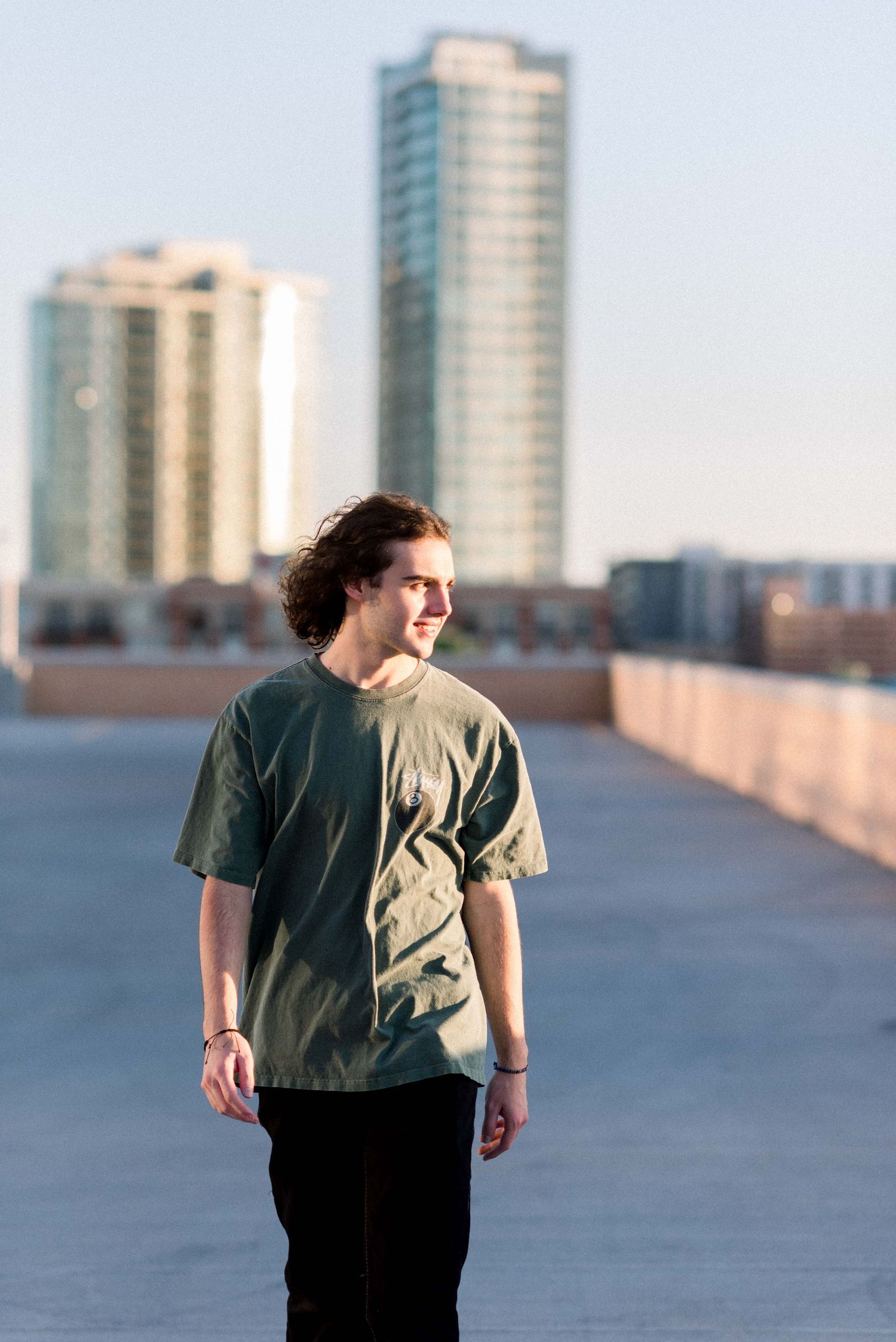 Urban fashion portrait with city skyscrapers in background during golden hour.