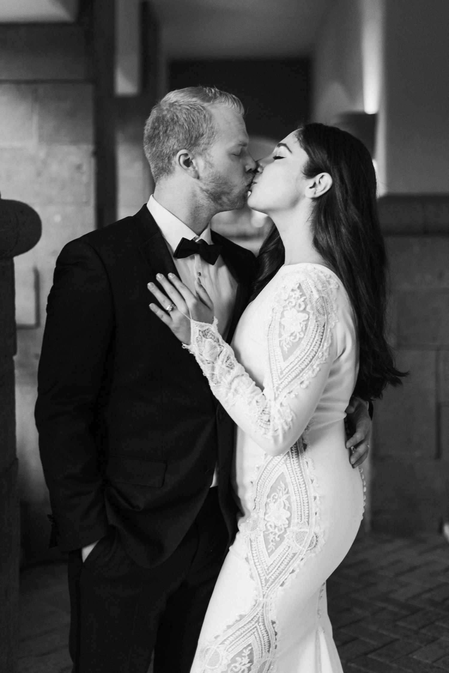 An intimate black and white portrait captures a romantic wedding day kiss.