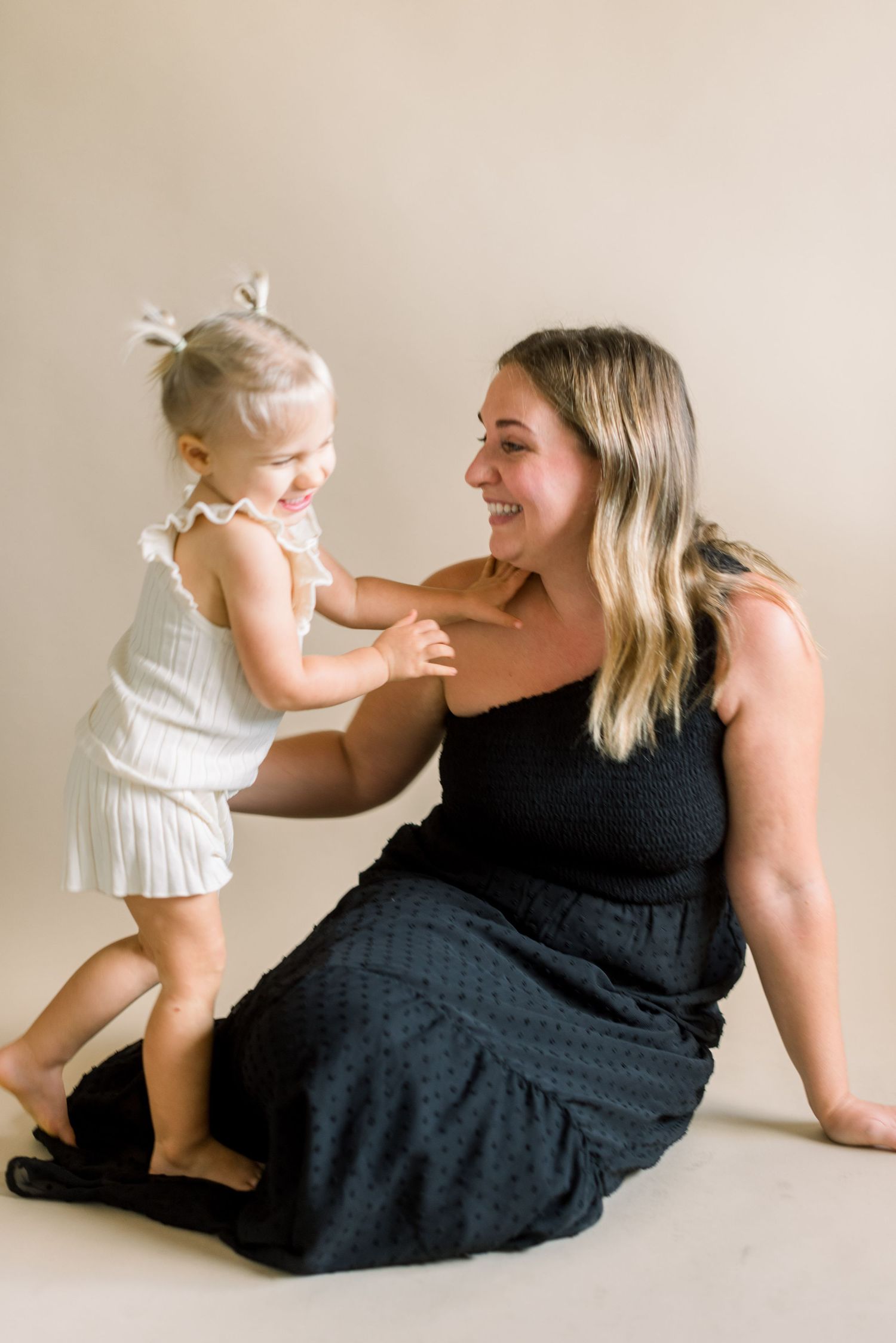 A candid moment of playful interaction between two people against a neutral backdrop.