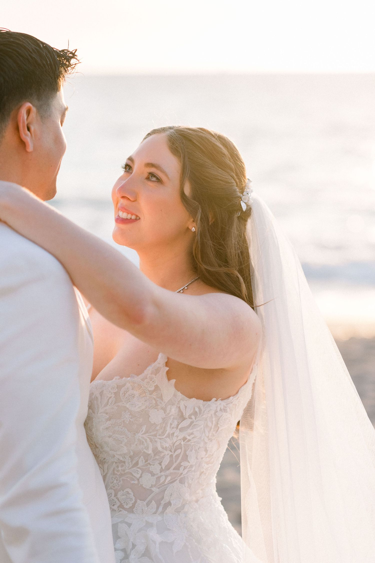 Joyful bride in strapless gown smiling at sunset.