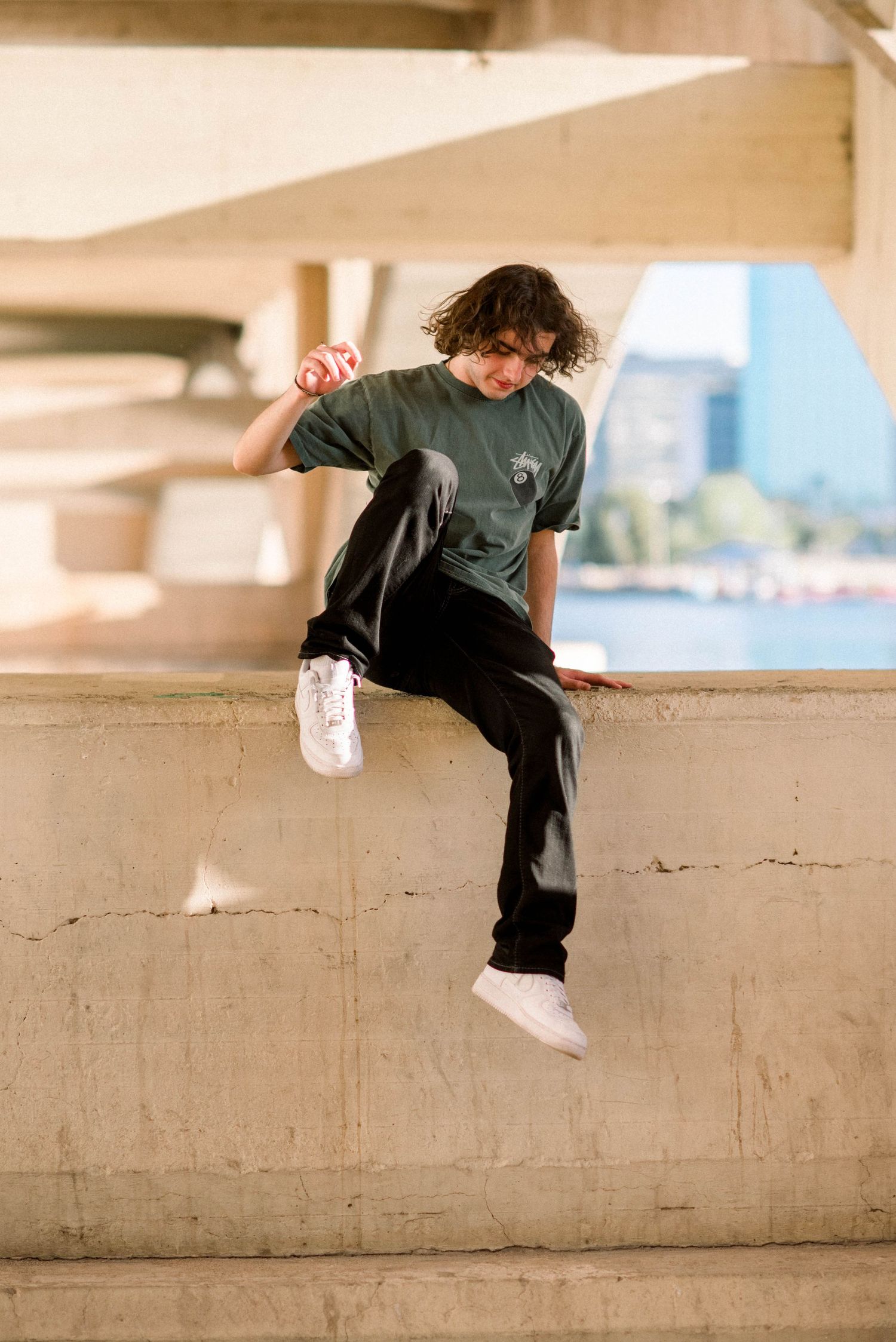 Action shot of person in green shirt jumping or climbing on concrete ledge.