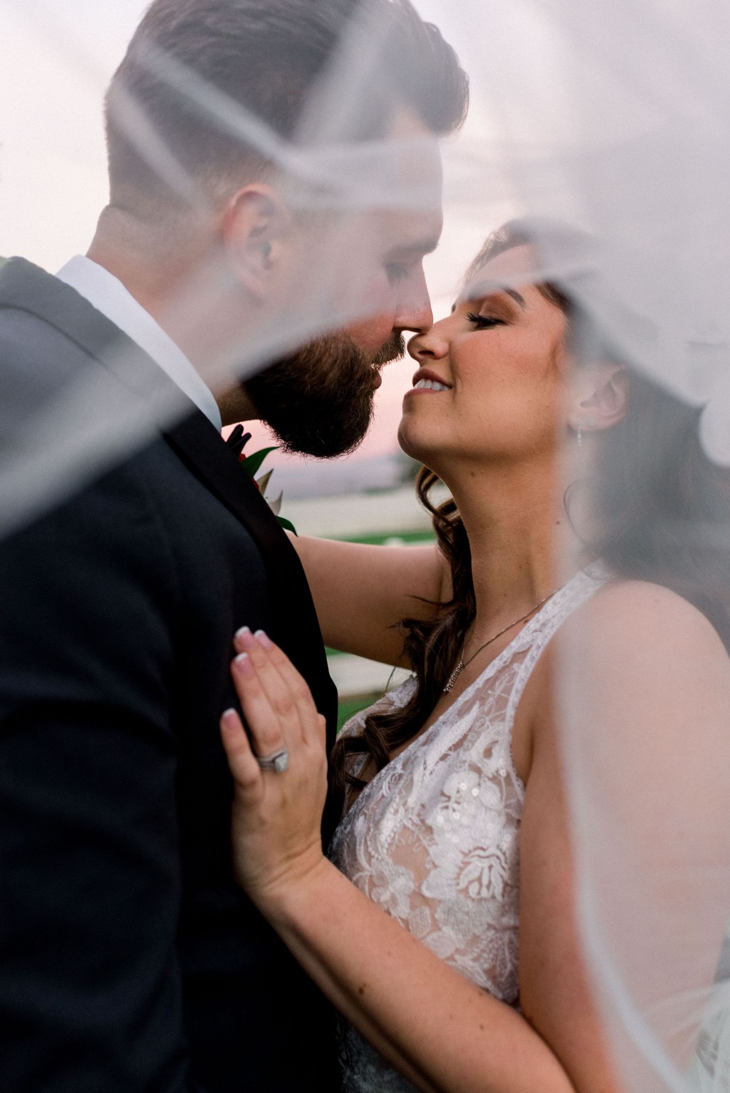 Romantic close-up of bride and groom sharing an intimate moment under a wedding veil.